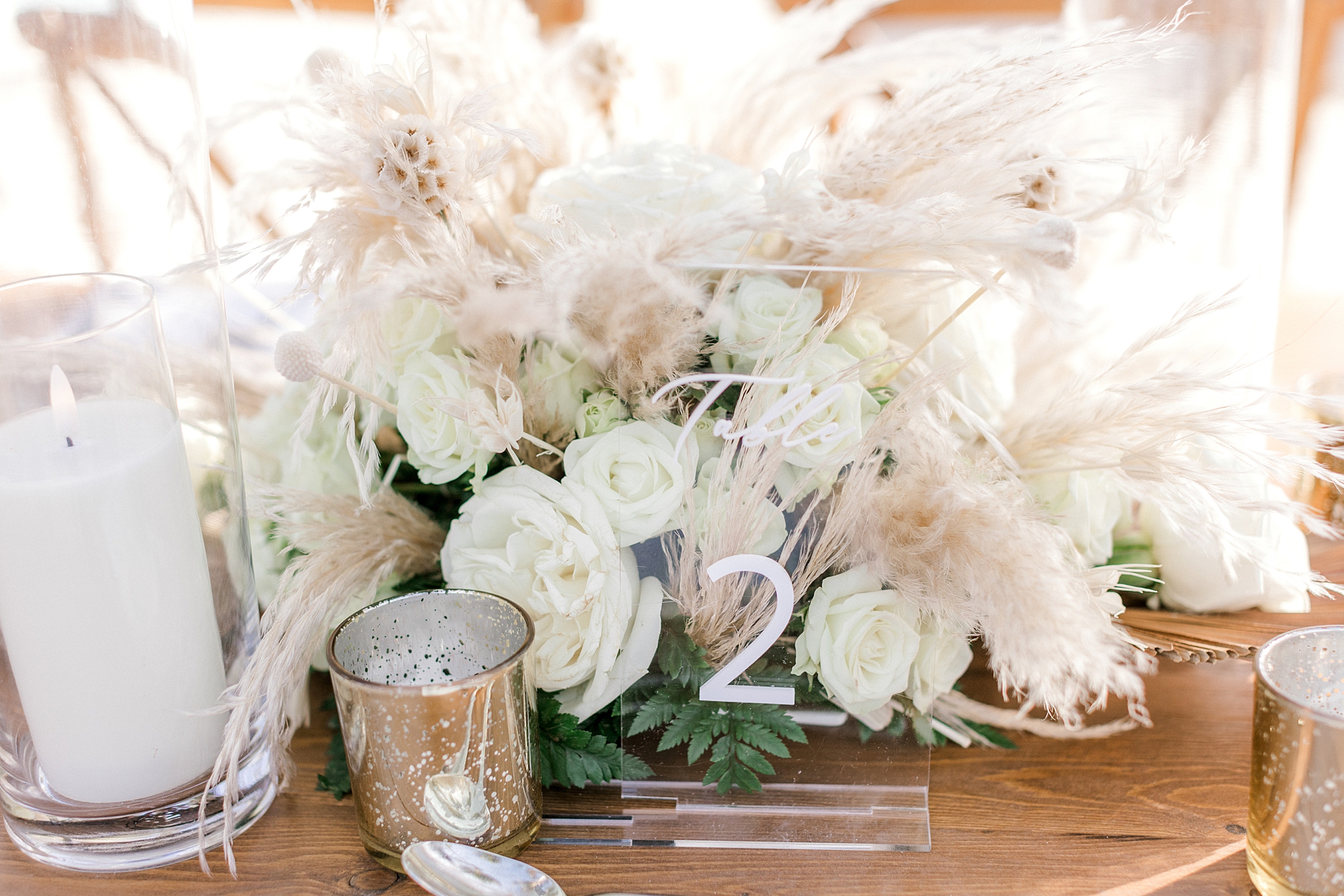 ivory rose centerpieces with tan accents and acrylic table numbers at Flamingo Island wedding reception