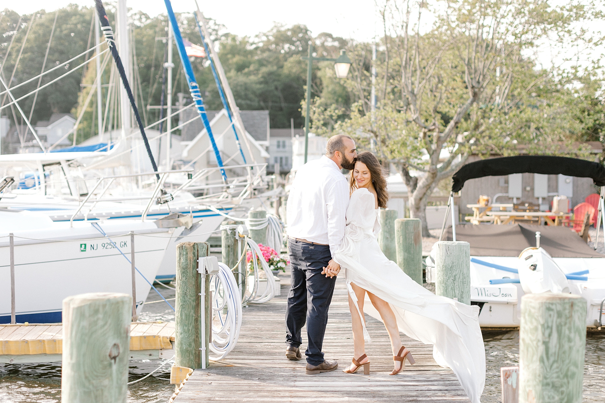 groom leans to kiss bride on wooden dock before getting on boat on Toms River