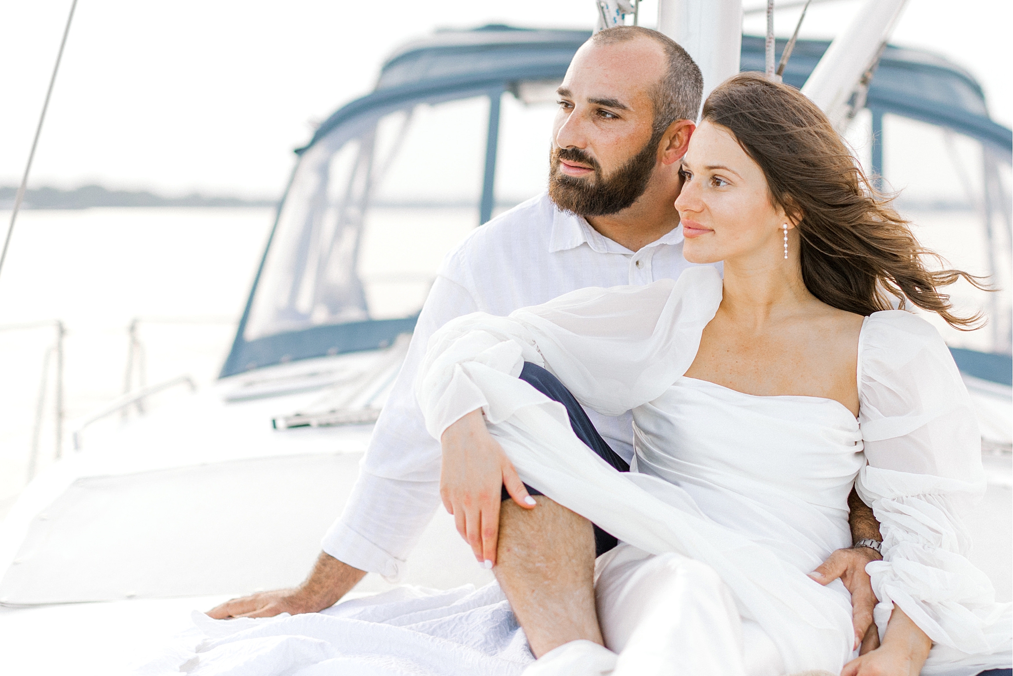 engaged couple sits on front of sailboat during Toms River engagement session