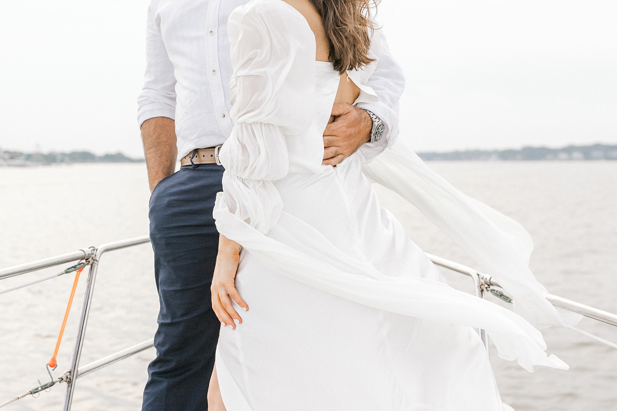 engaged couple hugs on front of sailboat during Toms River engagement session