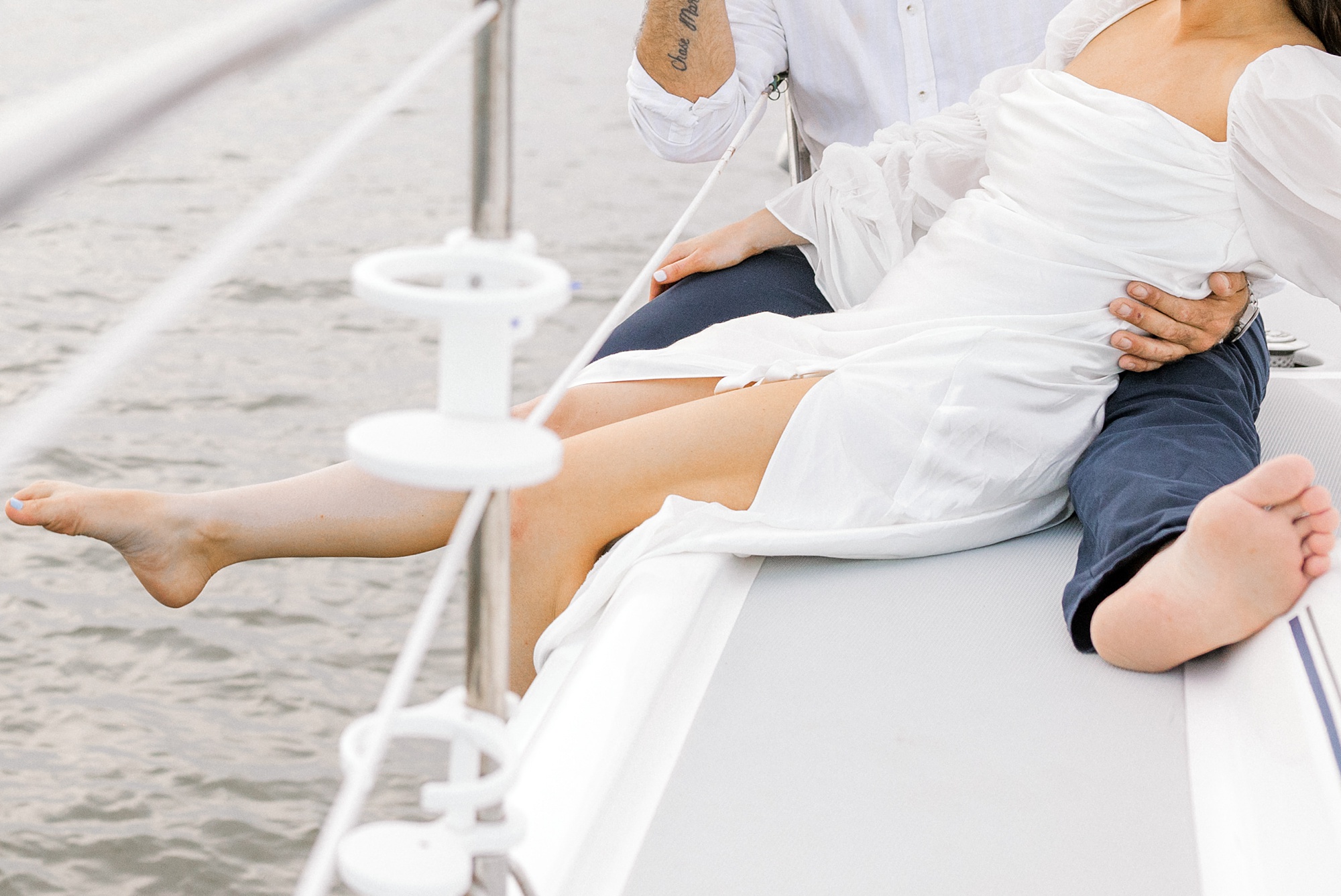 couple sits on edge of sailboat during Toms River engagement session