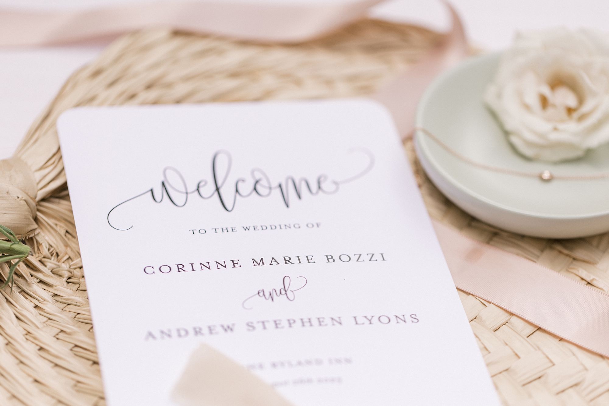 welcome card lays on woven fan with pink ribbon