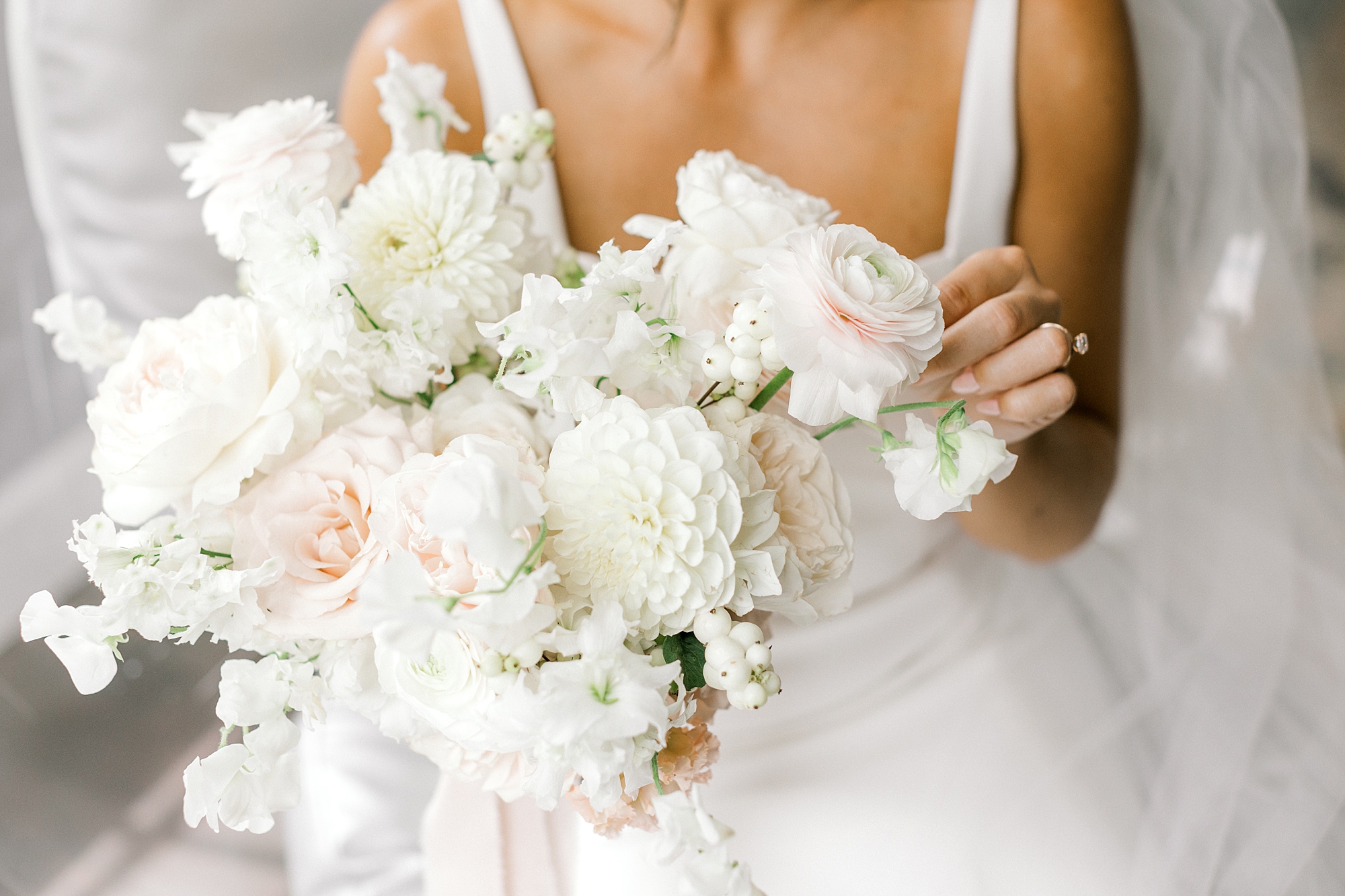 bride sits holding bouquet of pink and white flowers for summer wedding