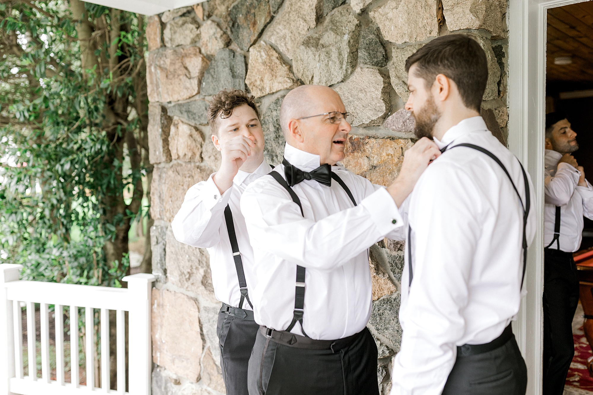 father helps groom into bowtie and suspenders before NJ wedding