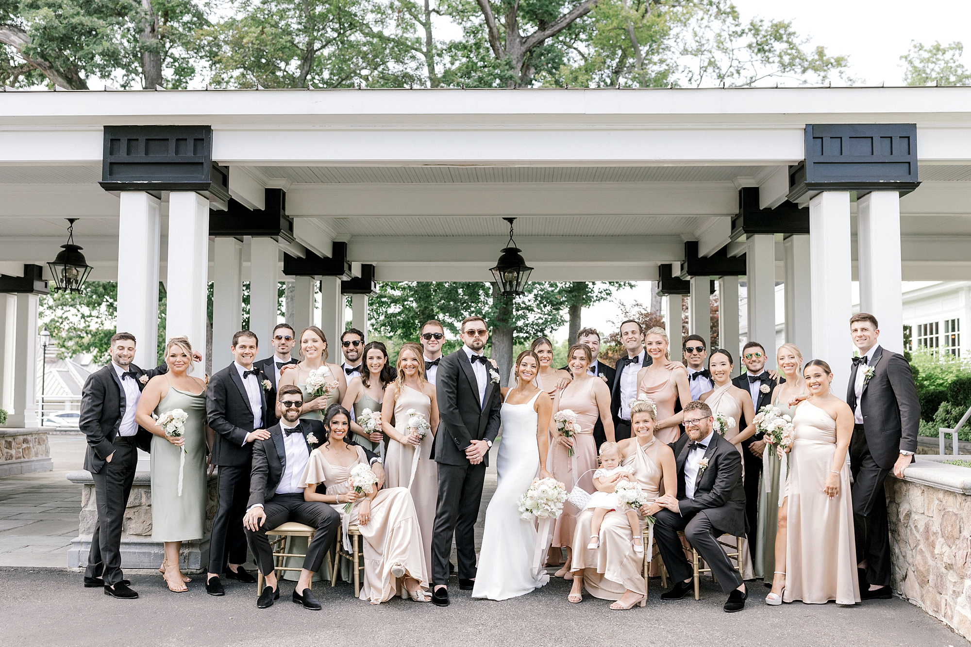 bride and groom stand with wedding party around them in front of awning at Ryland Inn