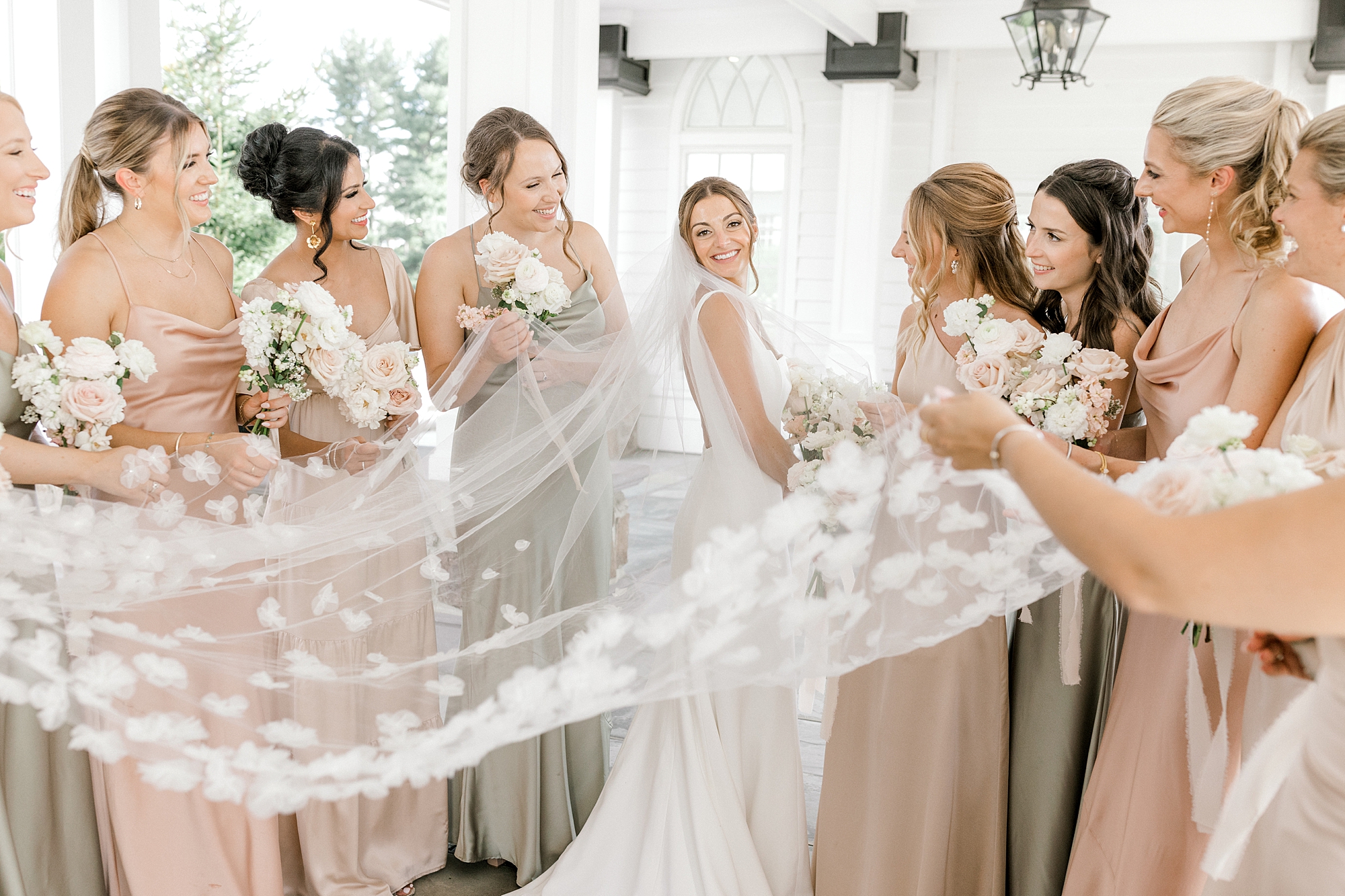 bride turns showing off veil with bridesmaids in pink and green