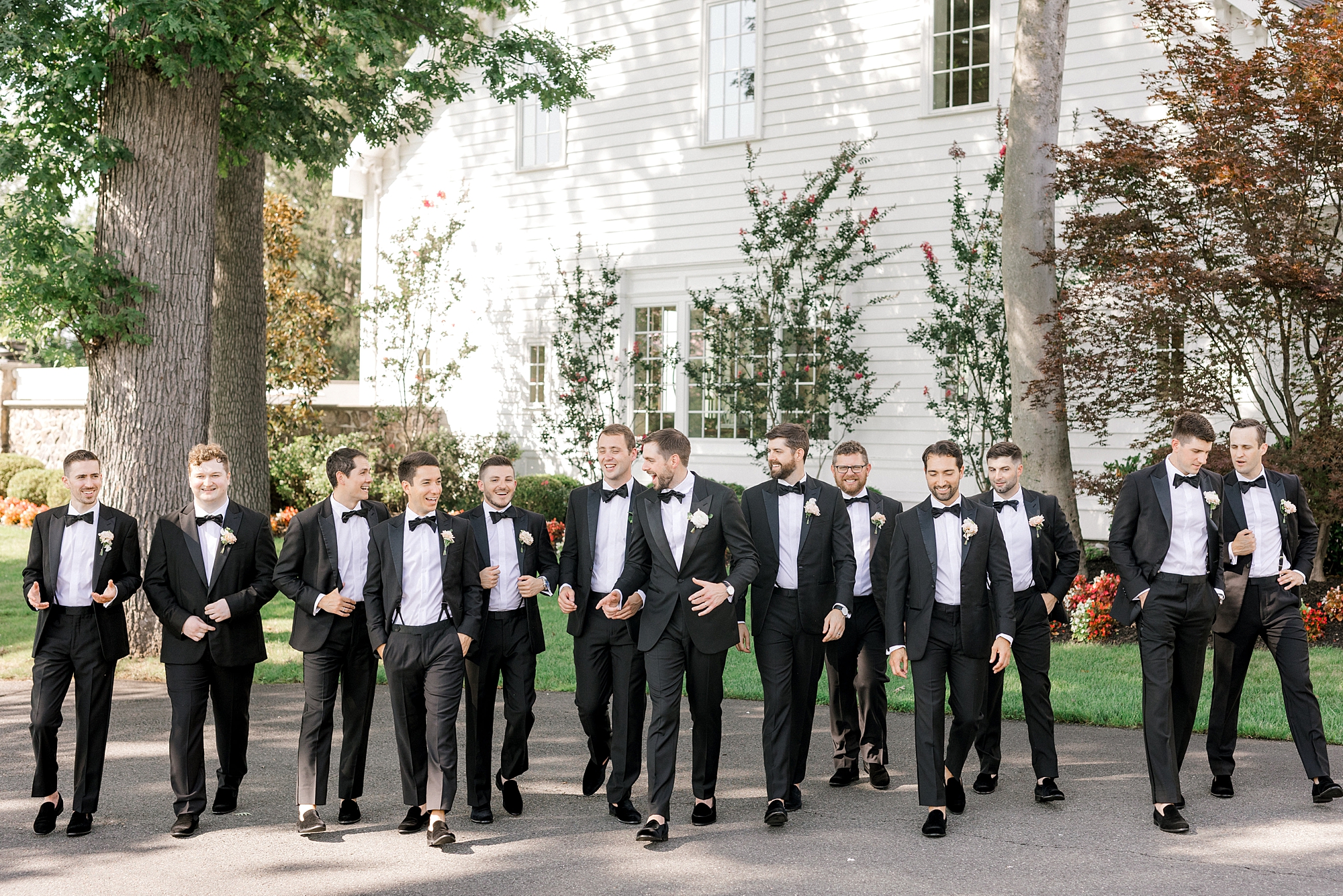 groom walks with groomsmen in front of Ryland Inn in black suits