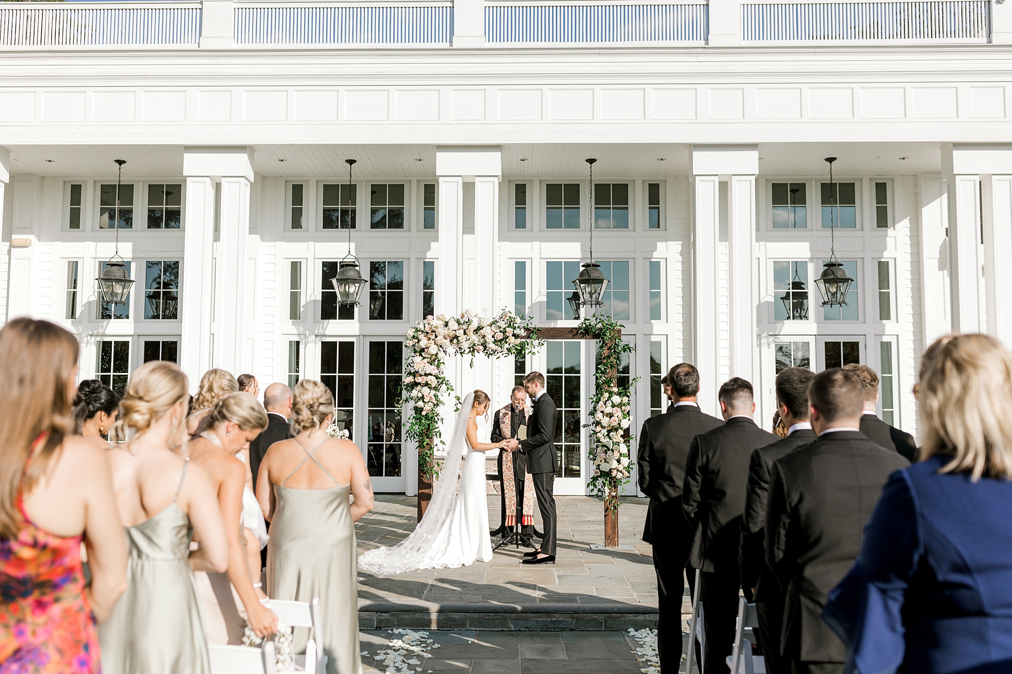 bride and groom exchange vows during summer wedding ceremony on patio at Ryland Inn
