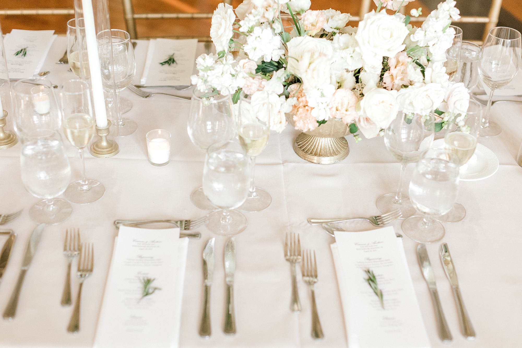 gold, white, and pink place settings in front of white and pink flower centerpieces