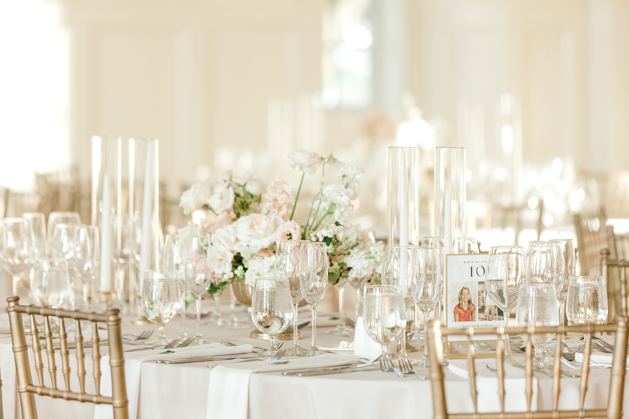 luxurious summer wedding reception tables capes with gold silverware and candles in tall glass vases
