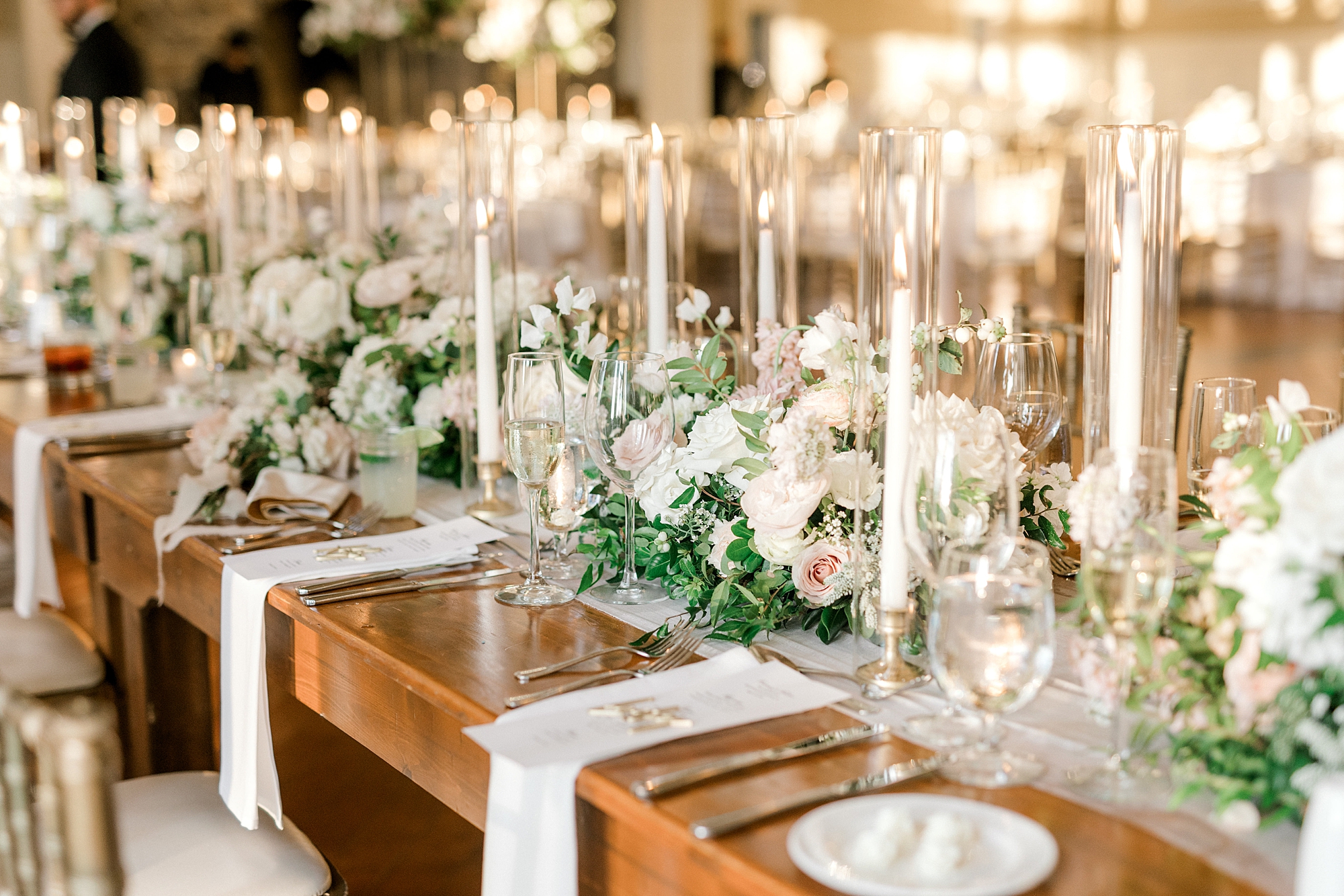 family style reception place settings with tall taper candles, greenery runner and pink and white flowers