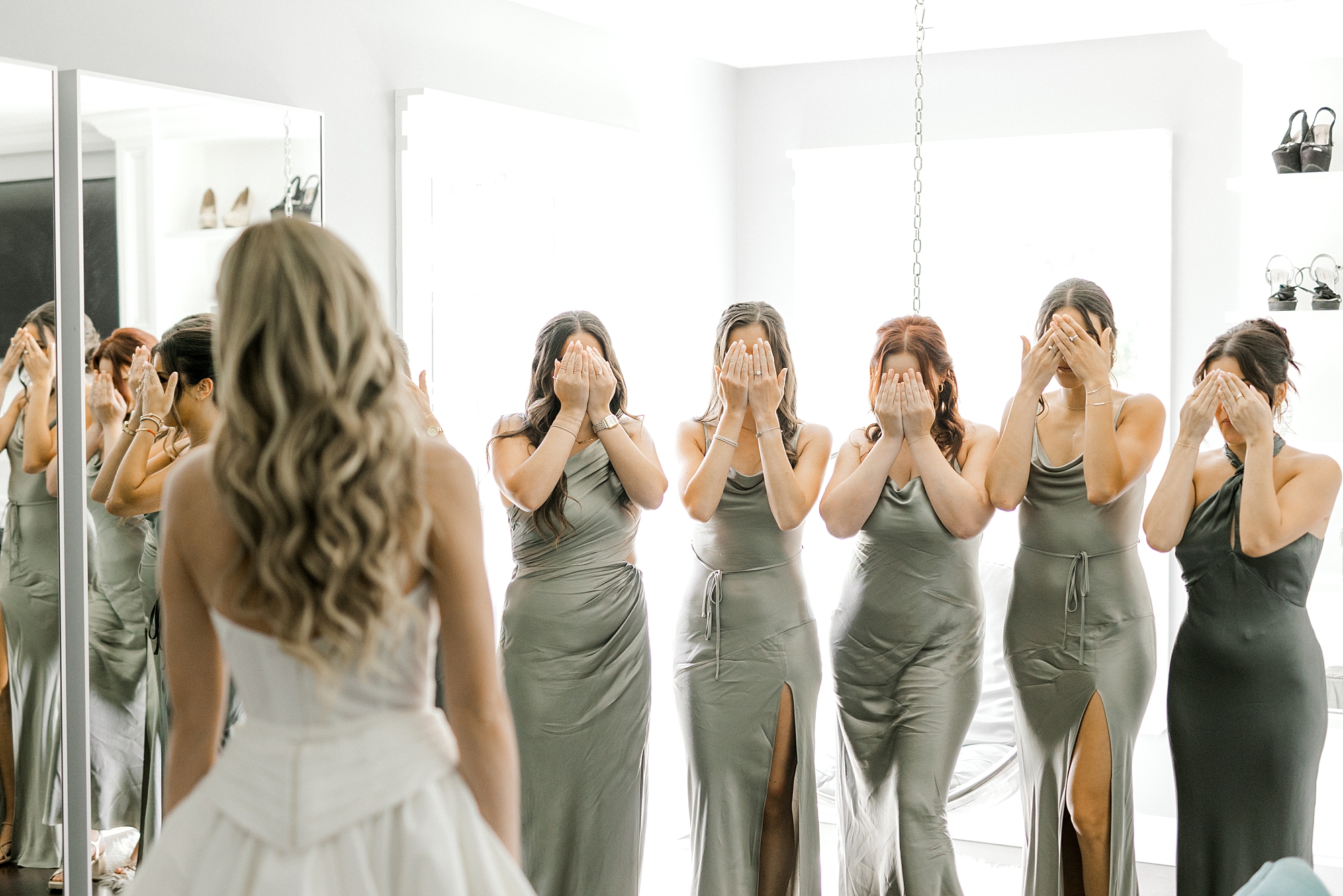 bridesmaids in chic sage green gowns cover eyes before first look with bride at Ryland Inn
