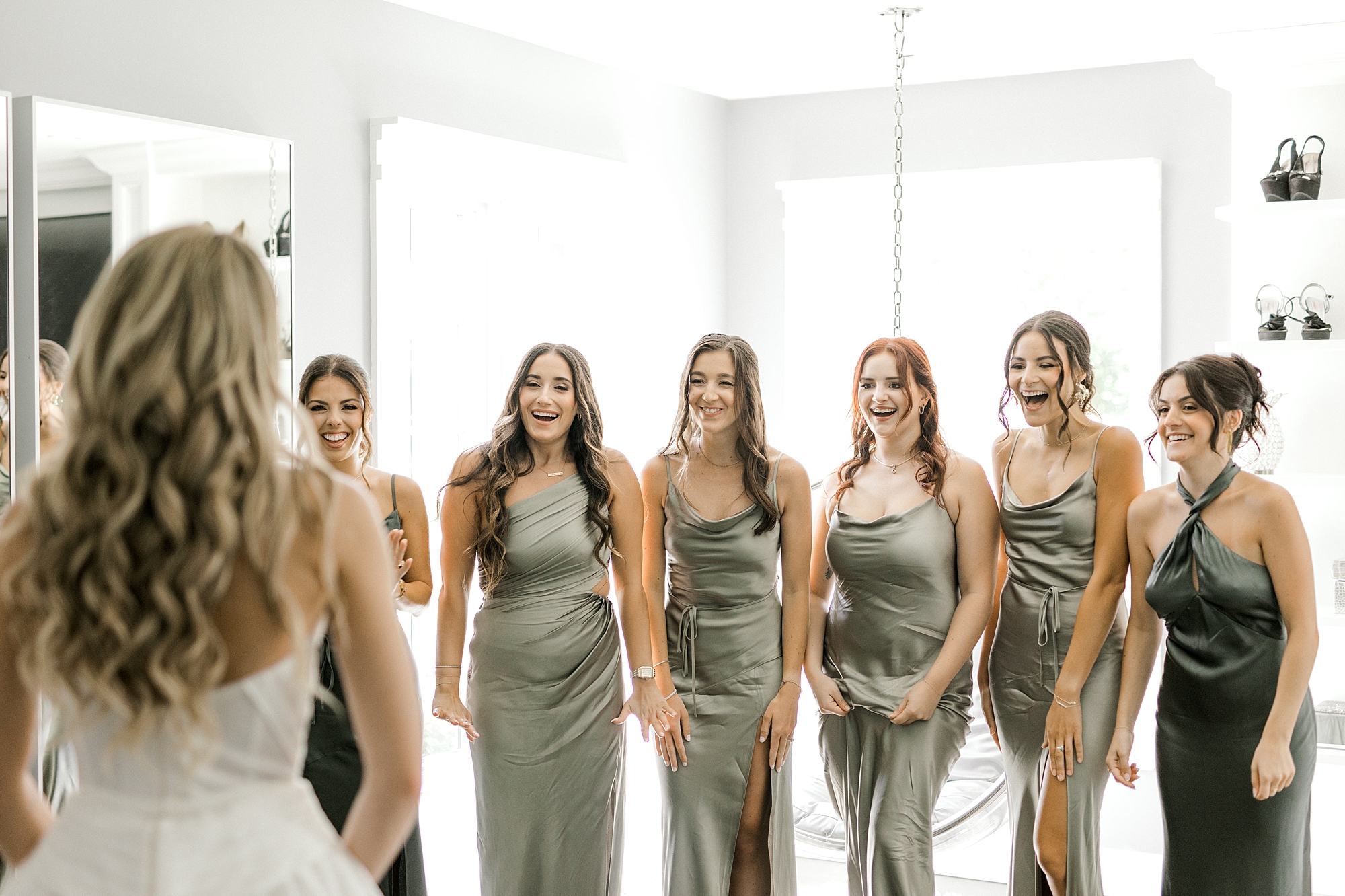 bride looks at bridesmaids in green gowns inside suite at Ryland Inn