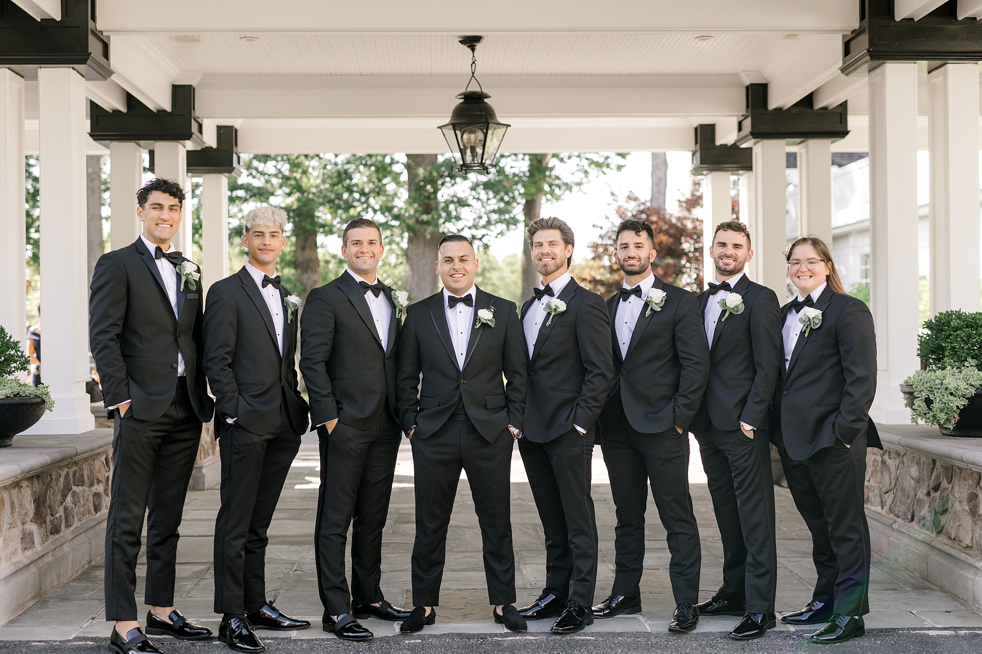 groom stands with groomsmen outside Ryland Inn in black suits