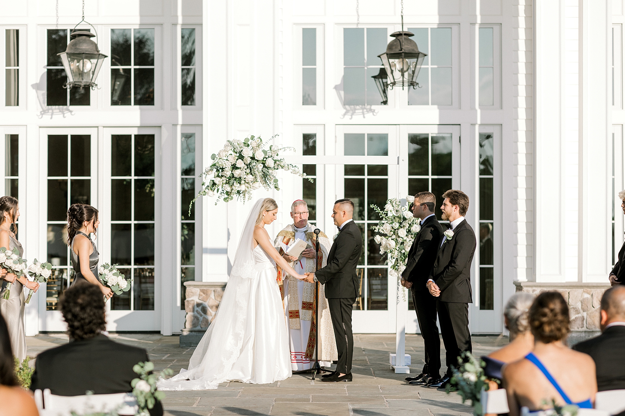 bride and groom hold hands on patio at Ryland Inn during summer wedding ceremony