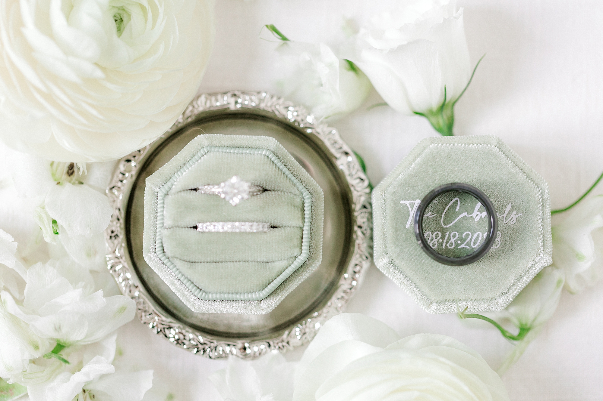 wedding rings rest in light green ring box with white flowers