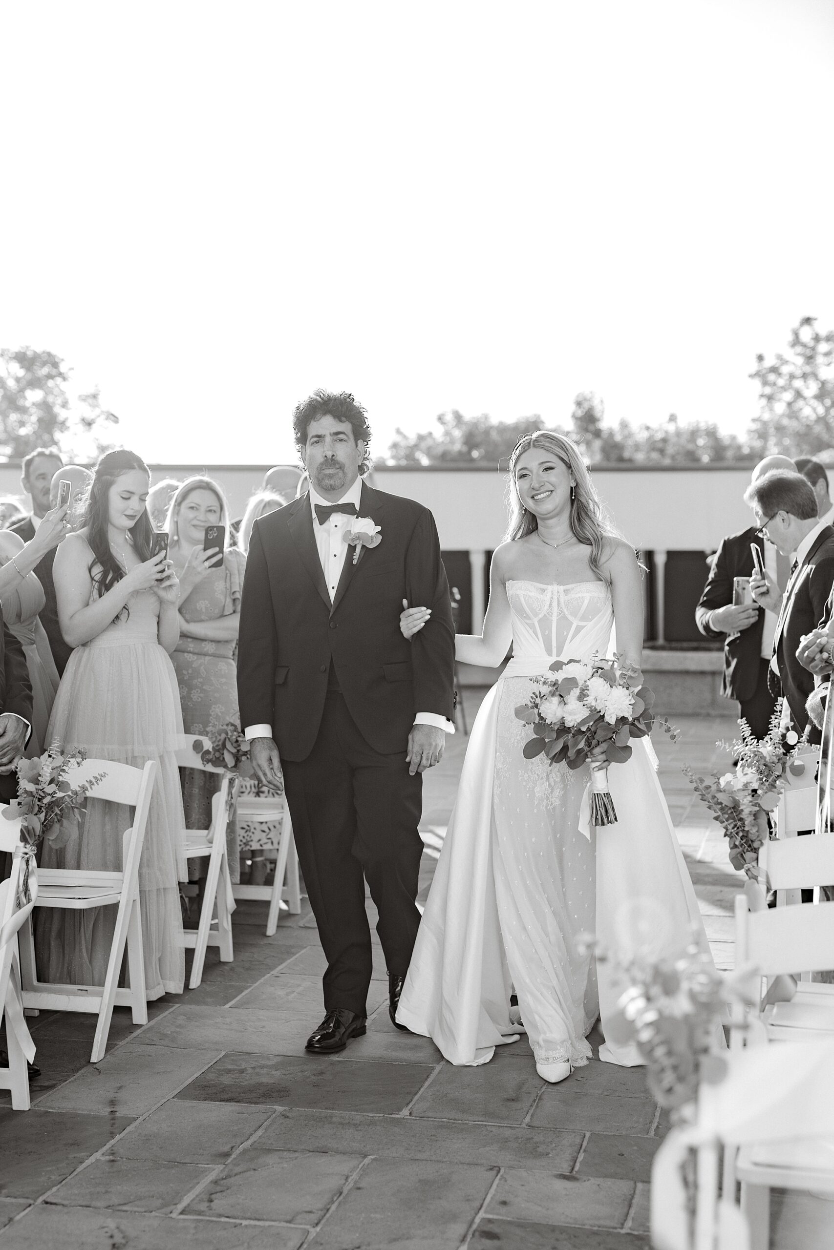 bride walks down aisle with father during summer wedding ceremony