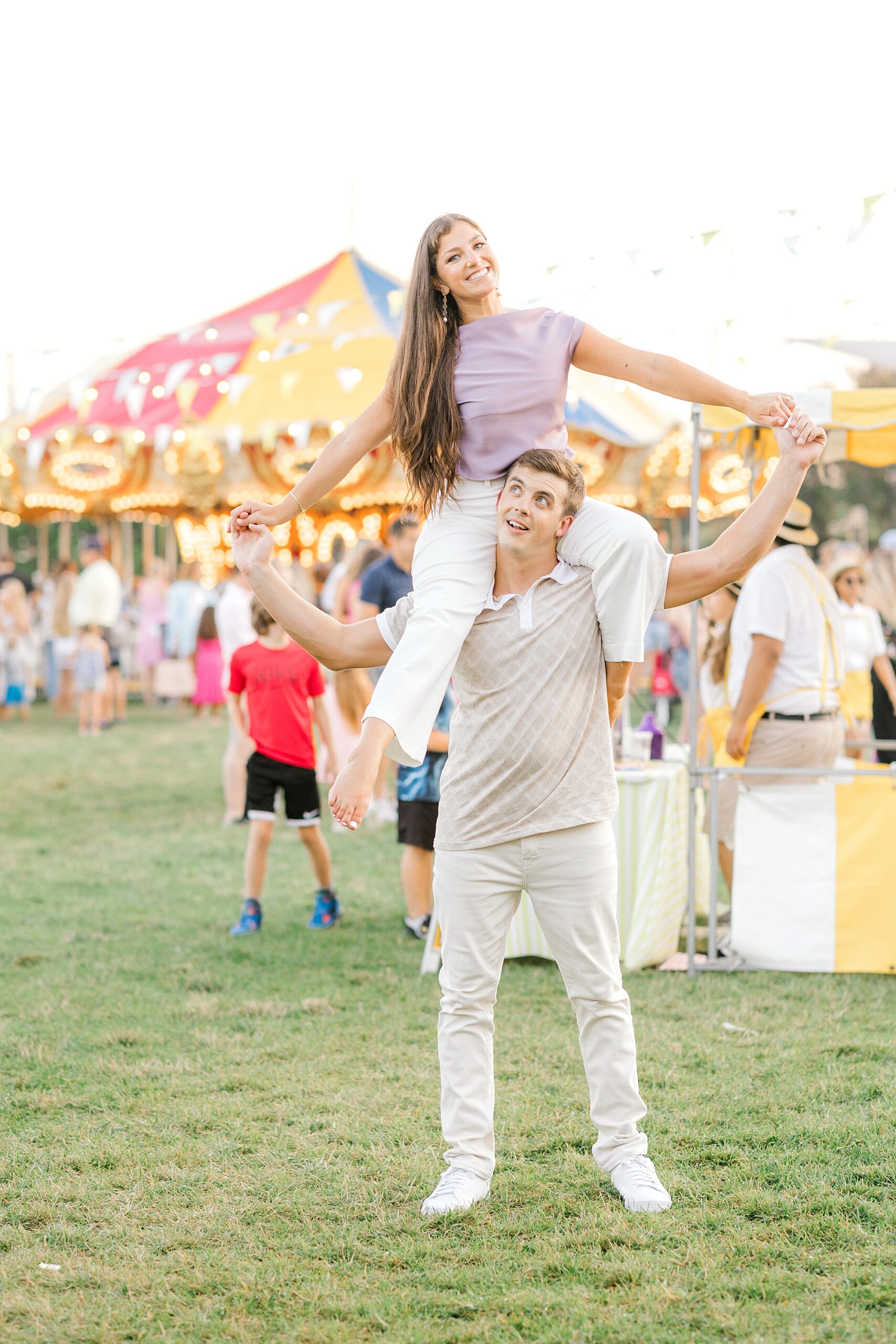 man holds fiancee on shoulders at Historic Cape May carnival