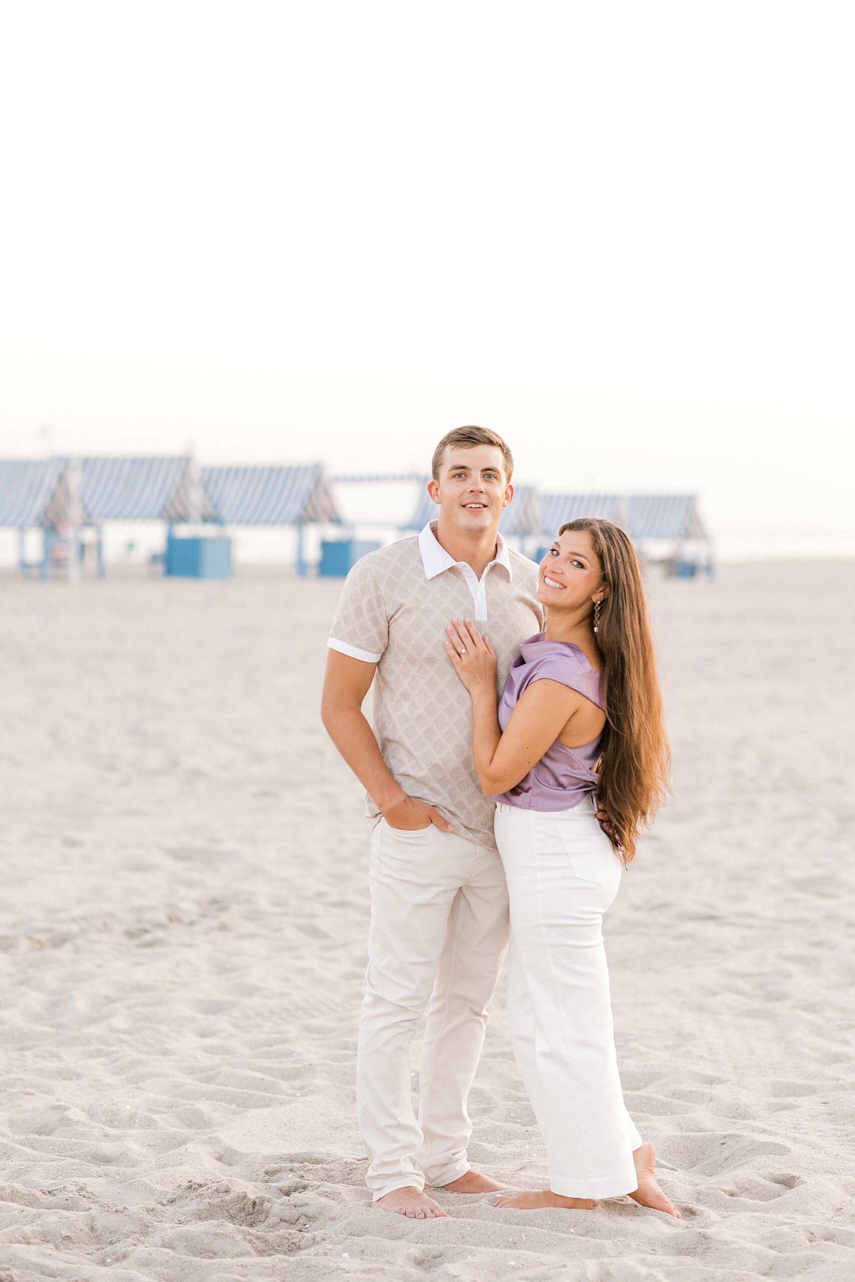 engaged couple stands together on sand of Historic Cape May beach