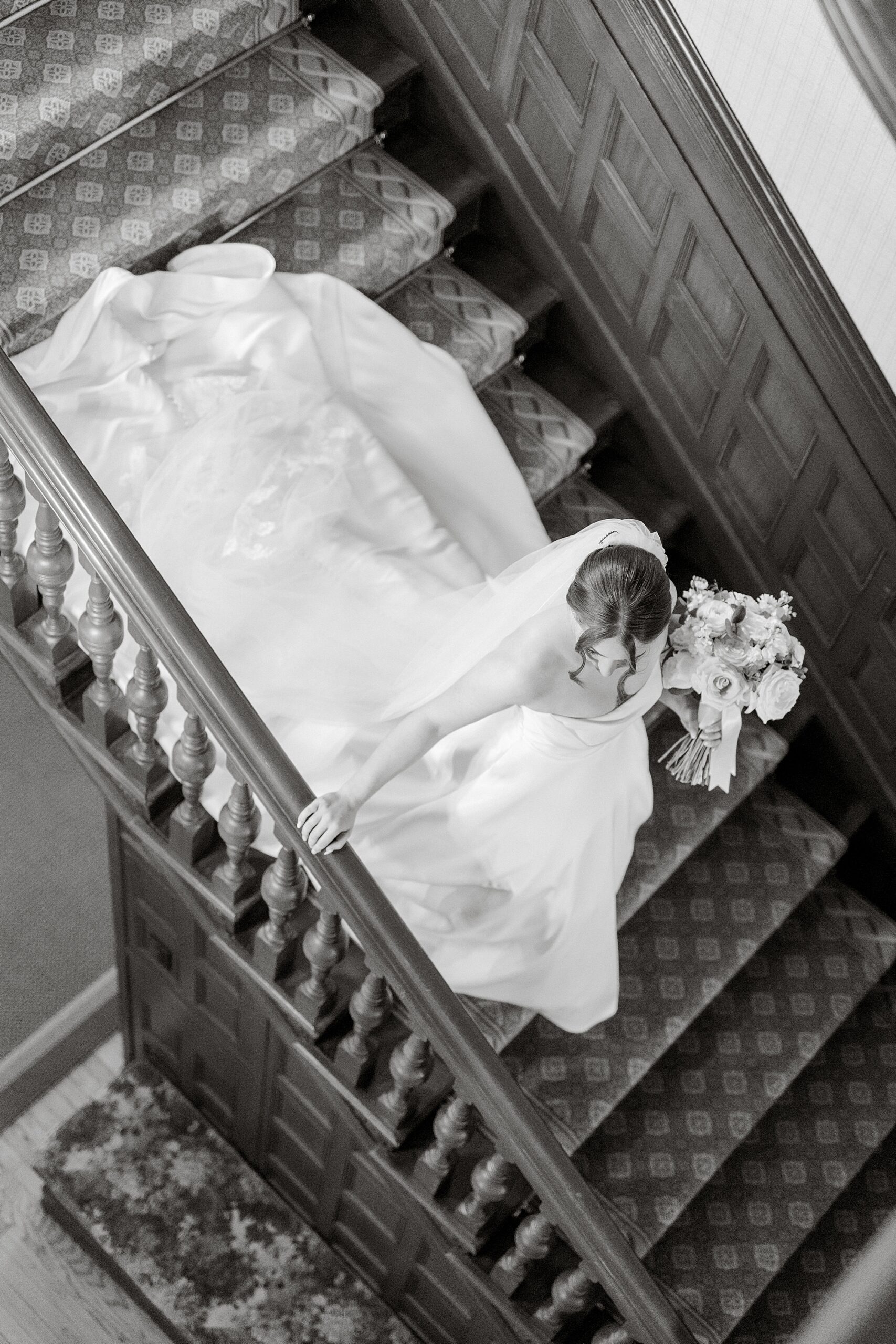 black and white photo of bride walking down staircase at the Farmhouse