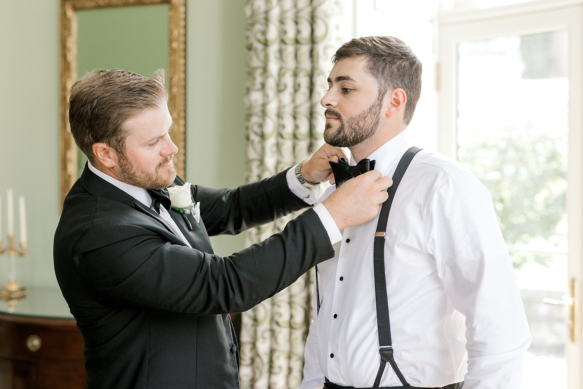 groomsman adjusts bowtie for groom before NJ wedding