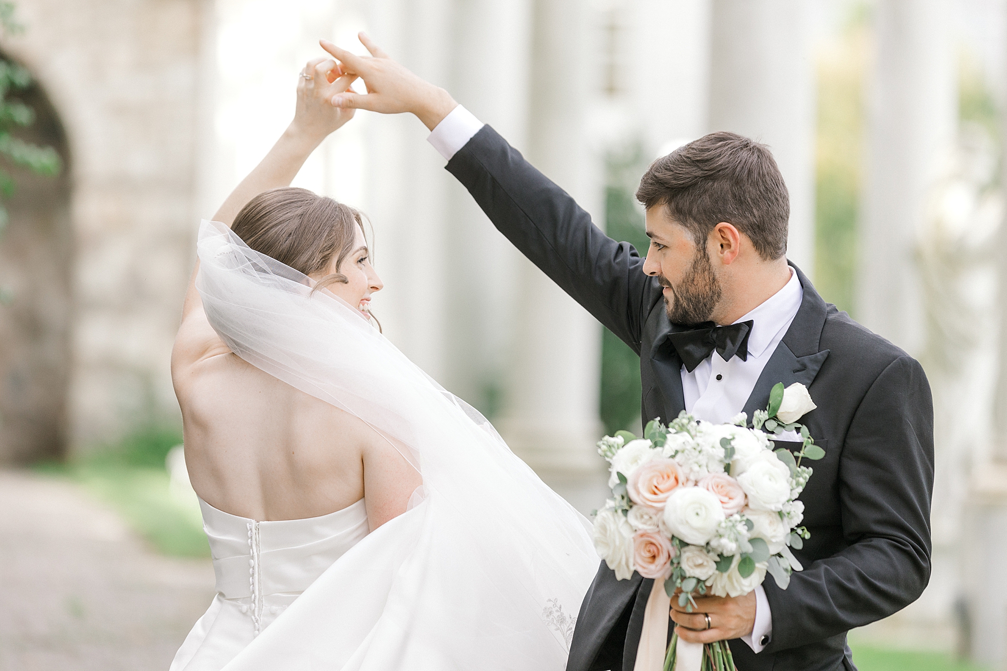 groom in black tux twirls bride under his arm in New Jersey