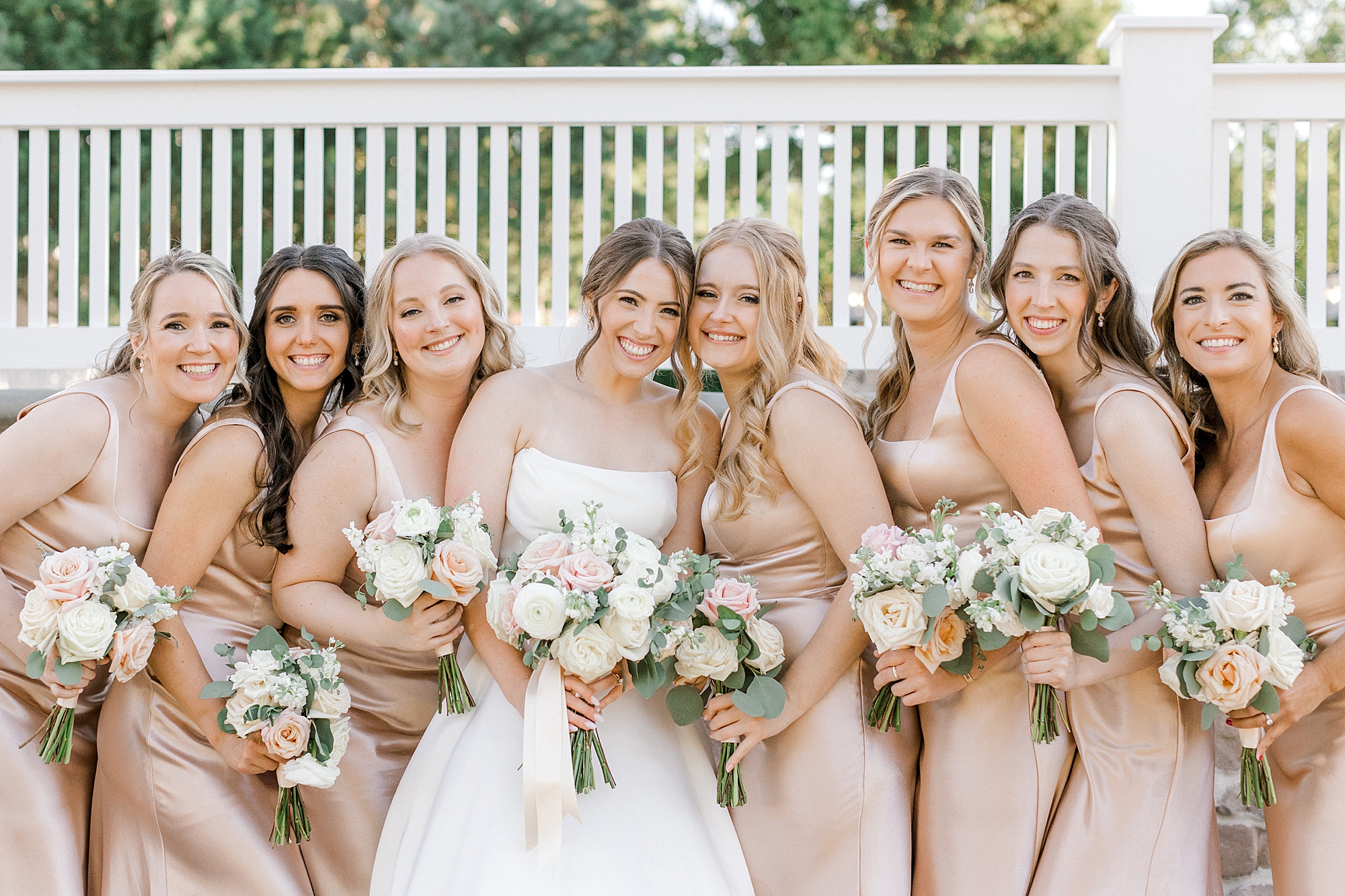 bride leans into bridesmaids wearing Champagne dresses