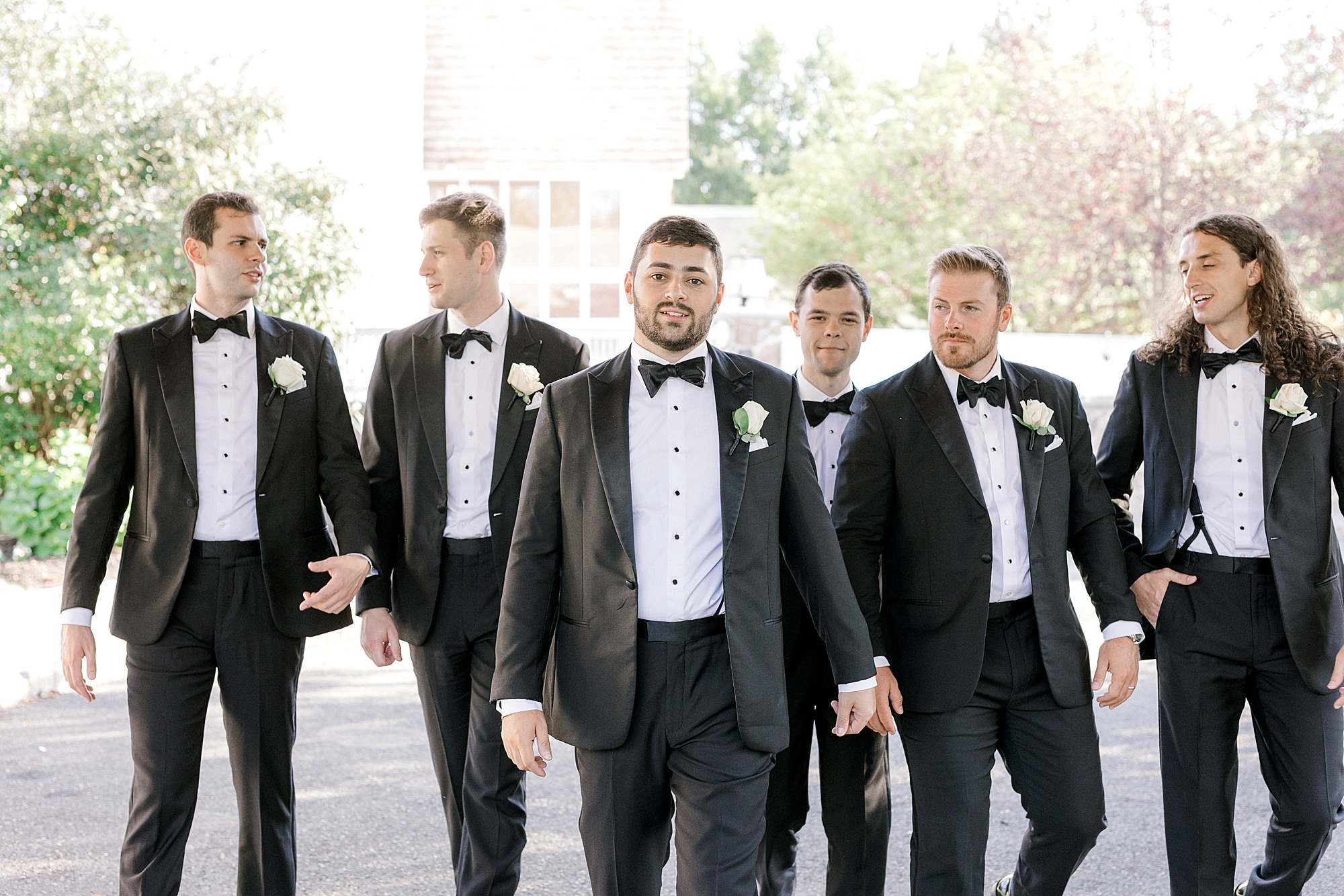 groom walks with groomsmen in black suits