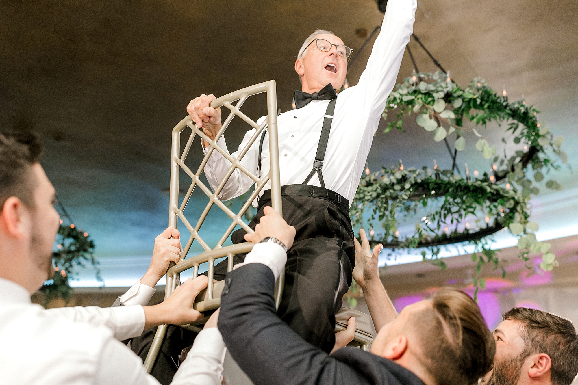 guests lift man up on chair during during Hampton NJ wedding reception