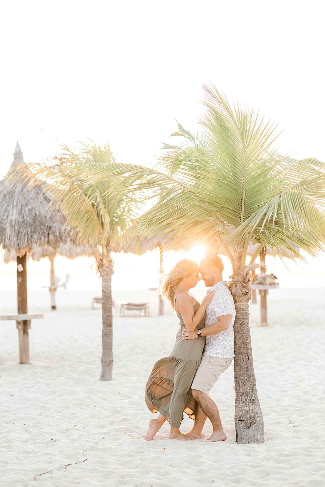couple under a palm tree at sunset in aruba