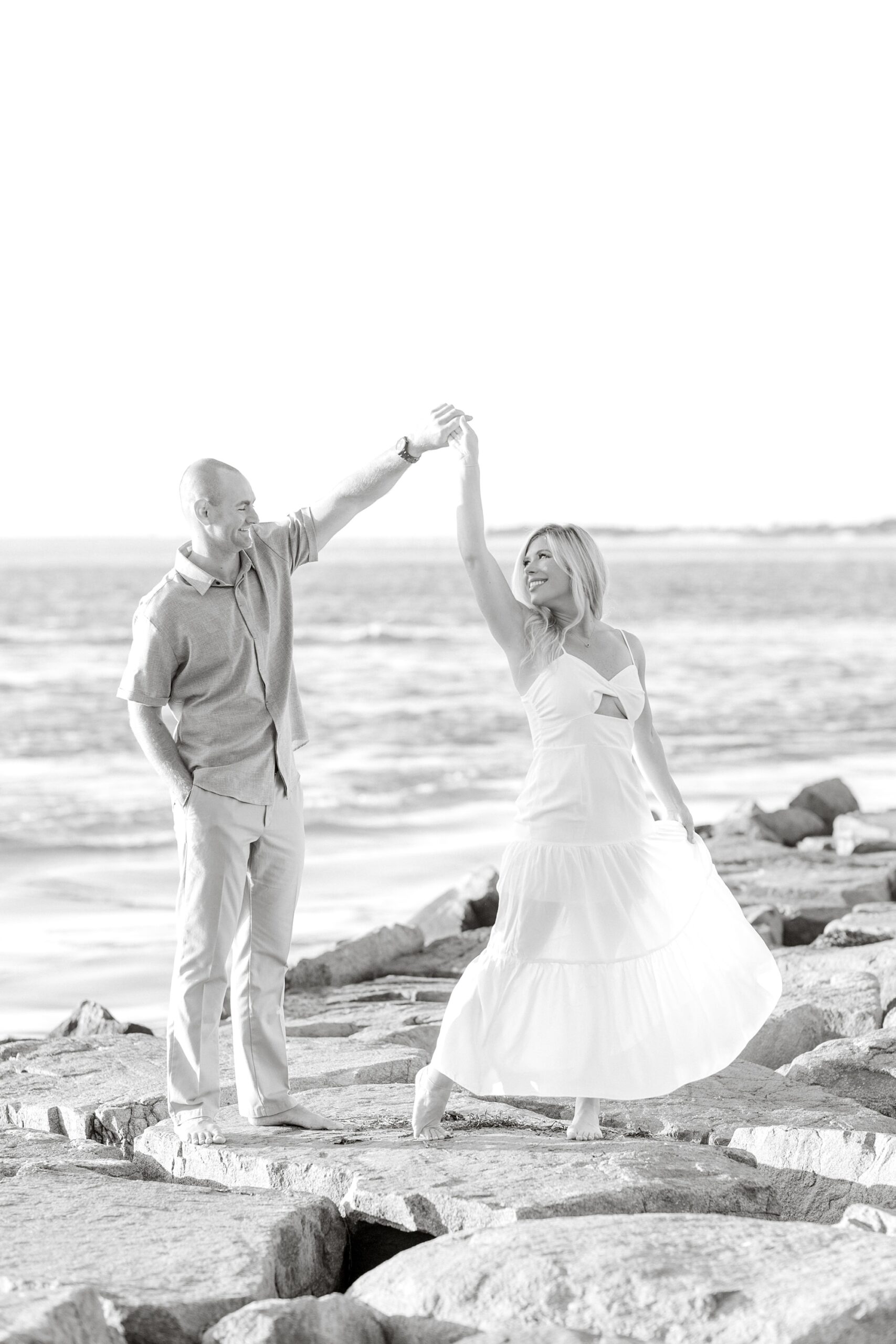 groom twirls bride standing on rocks on New Jersey beach