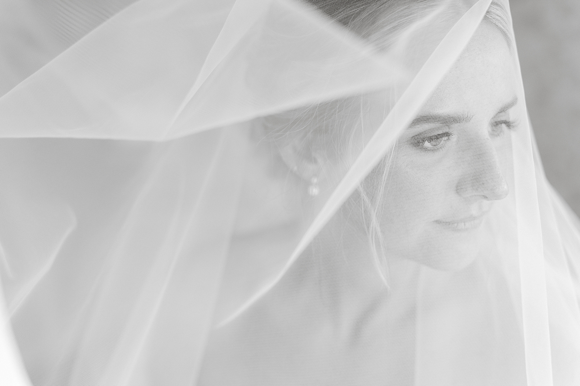 black and white portrait of bride looking over shoulder under veil