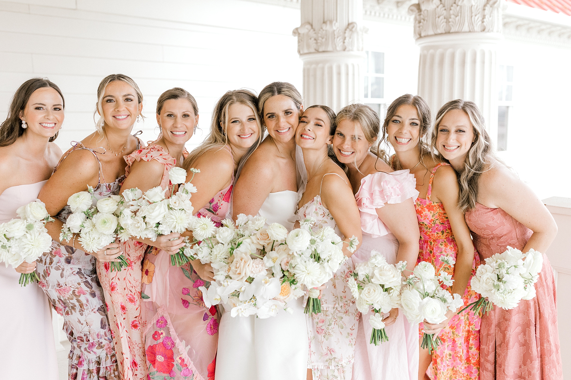 bride laughs with bridesmaids in mismatched pink and peach gowns at Mallard Island Yacht Club