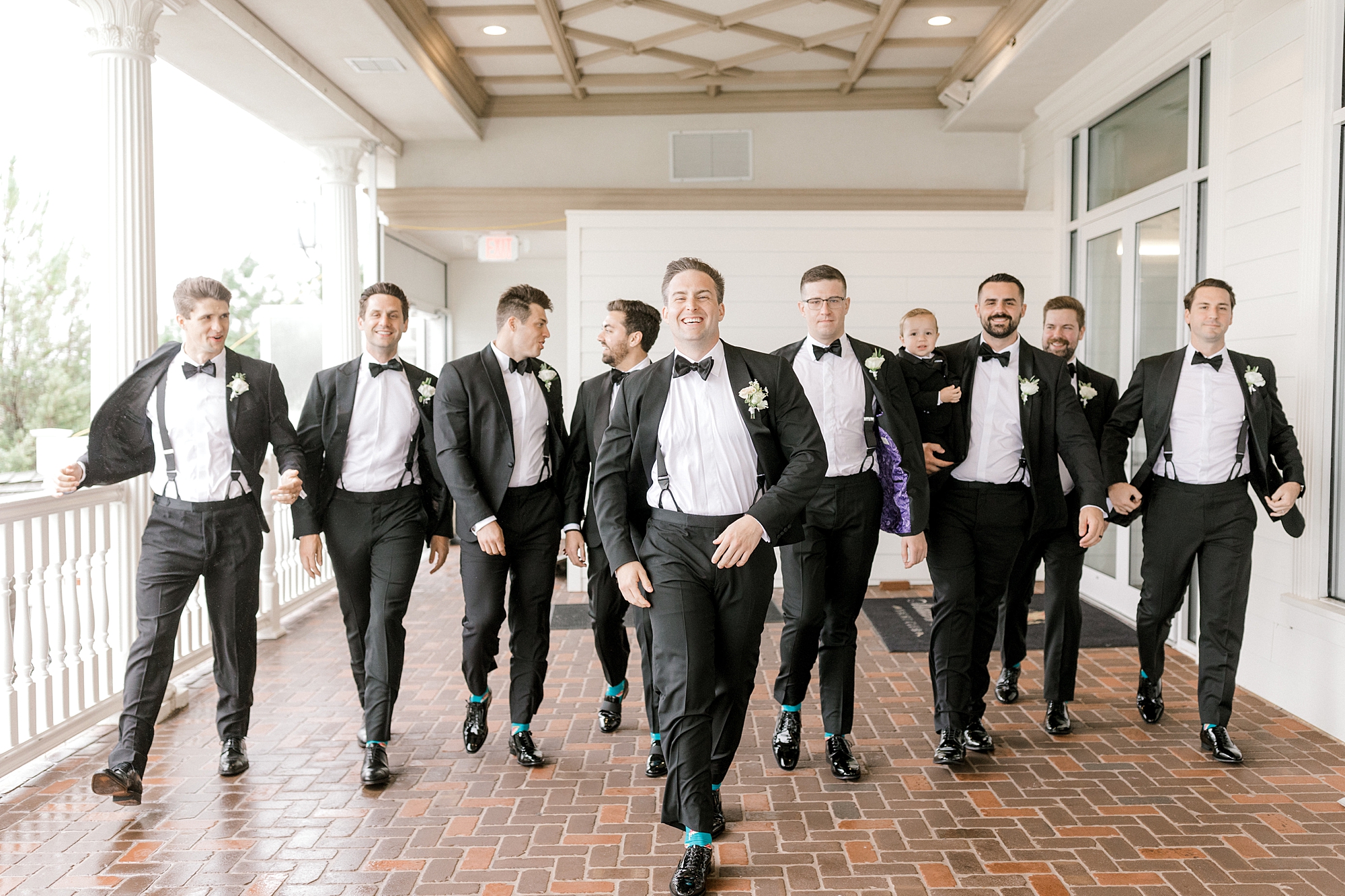 groom walks with groomsmen under walkway at Mallard Island Yacht Club