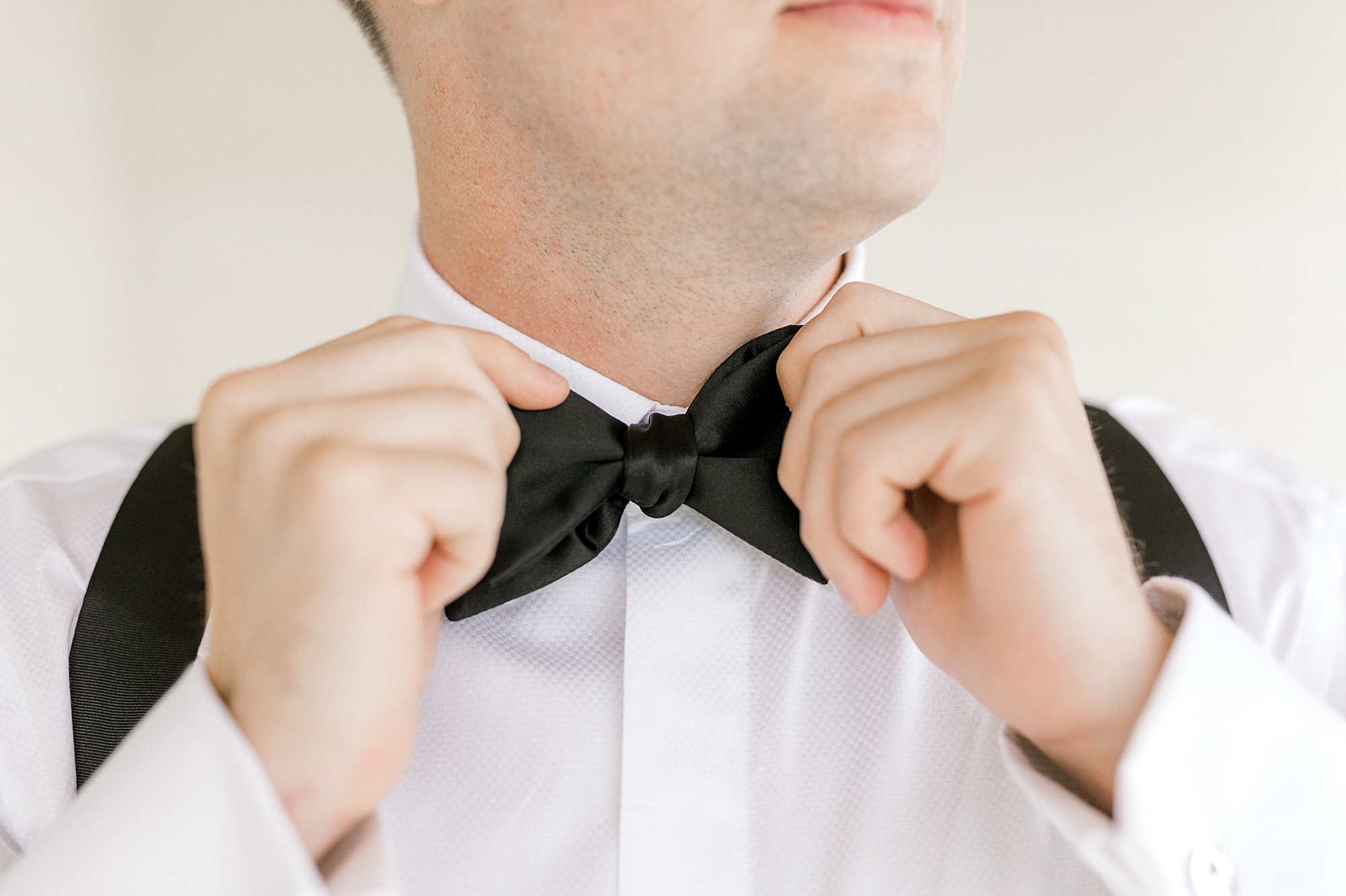 groom adjusts black tie before NJ wedding day