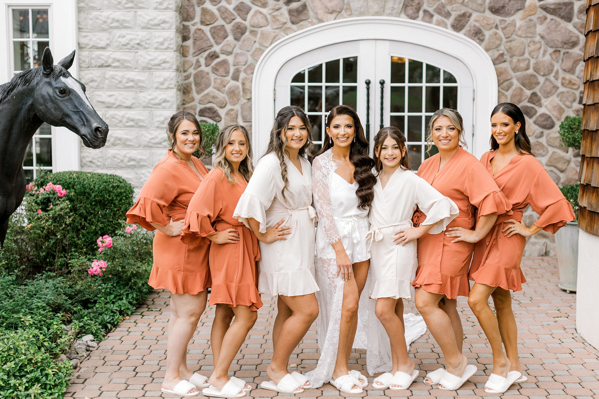 bride poses with bridesmaids in orange robes during fall wedding at Ryland Inn