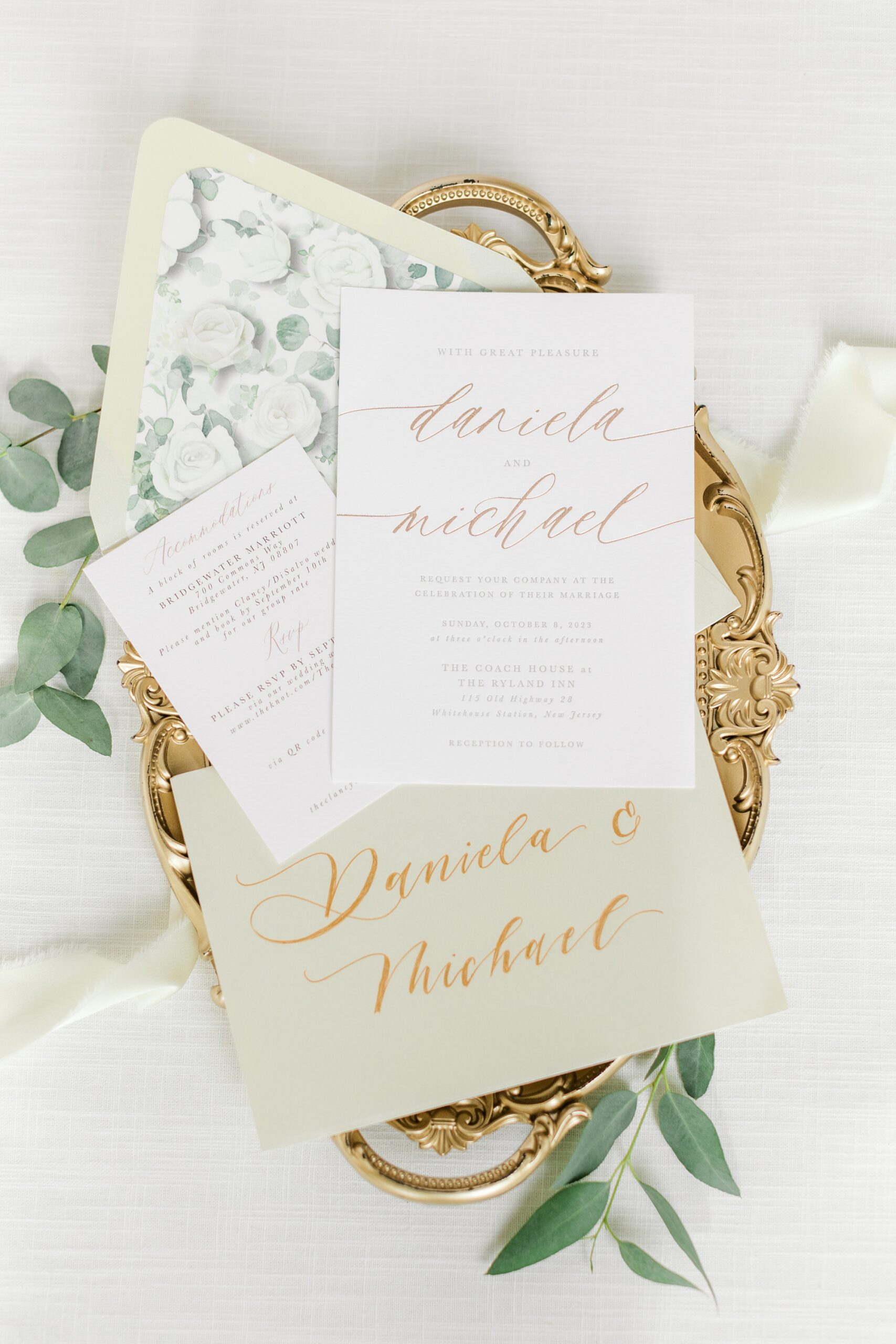 white and gold invitation suite rests on gold tray before fall wedding at Ryland Inn