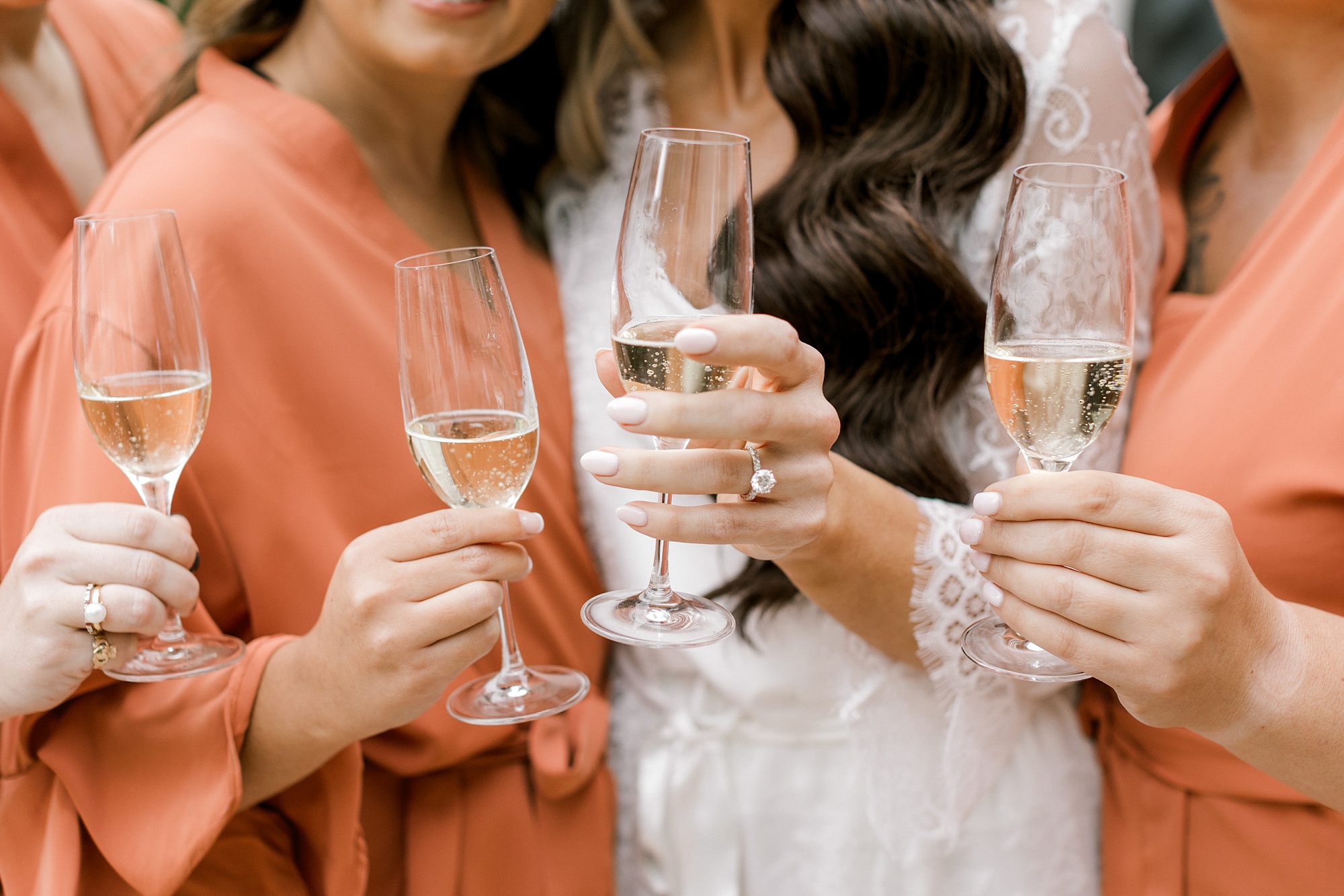 bride and bridesmaids in orange robes hold glasses of champagnes on morning of NJ wedding