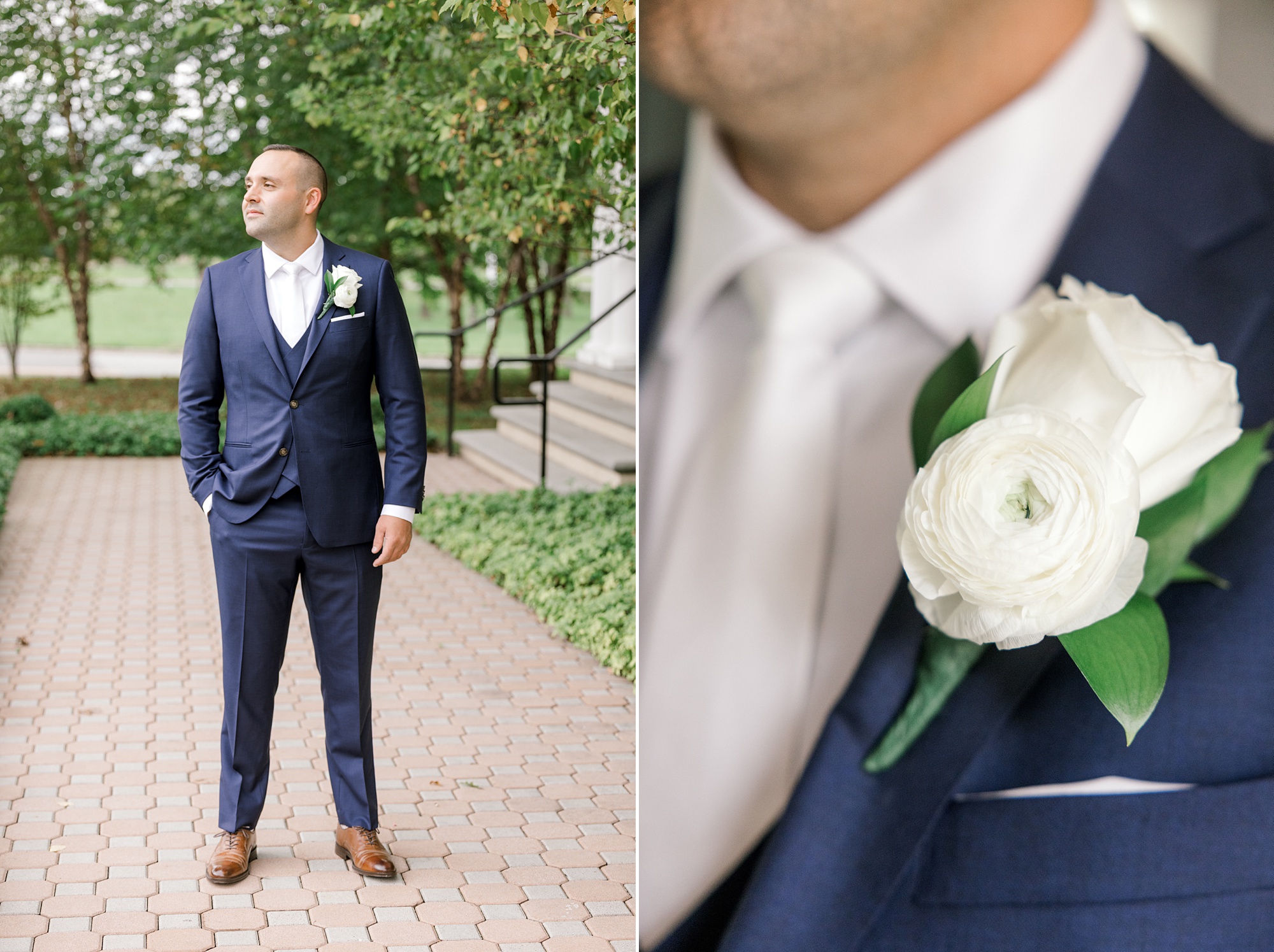 groom poses in navy suit with white rose boutonnière