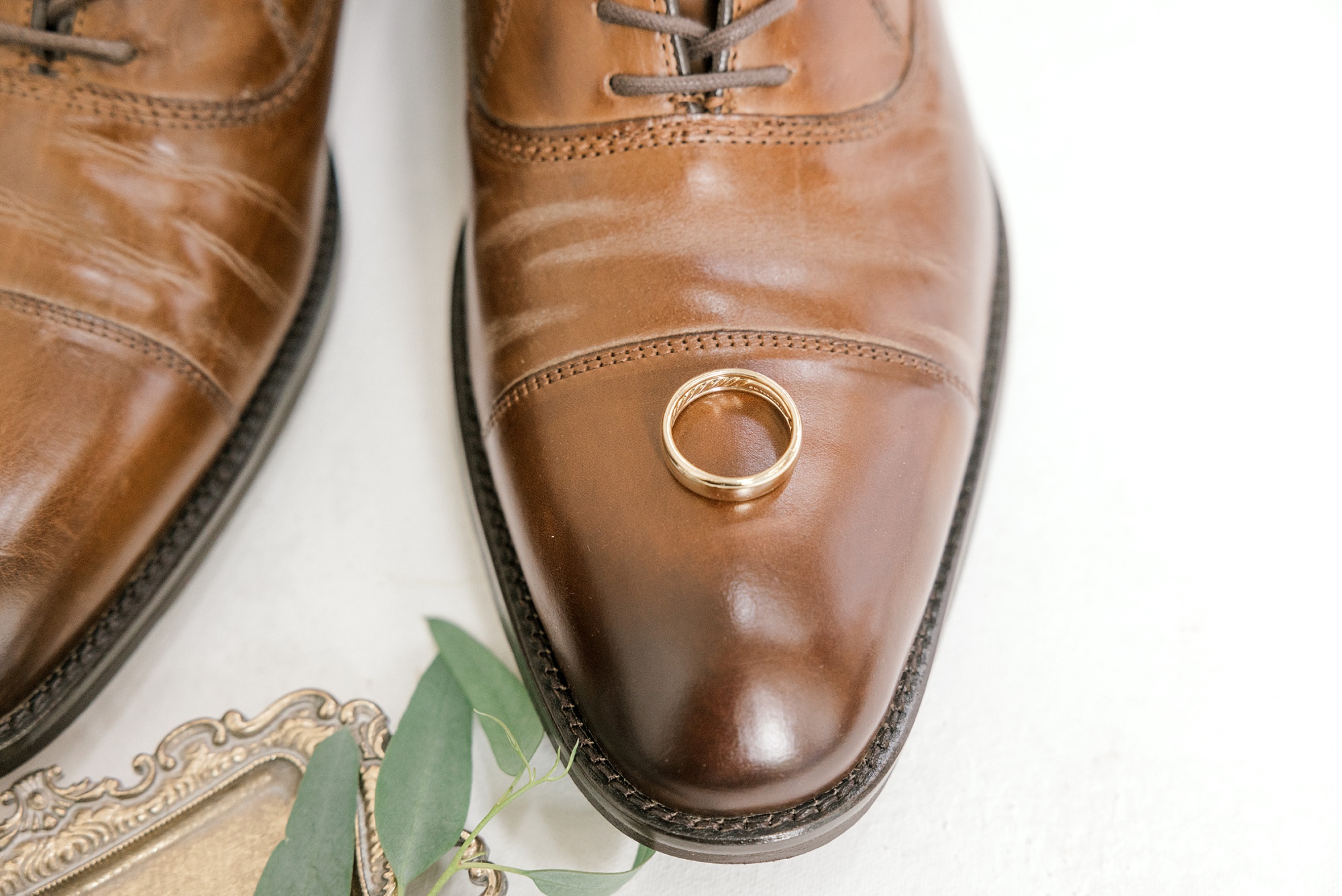 gold wedding band rests on groom's brown shoes for NJ wedding