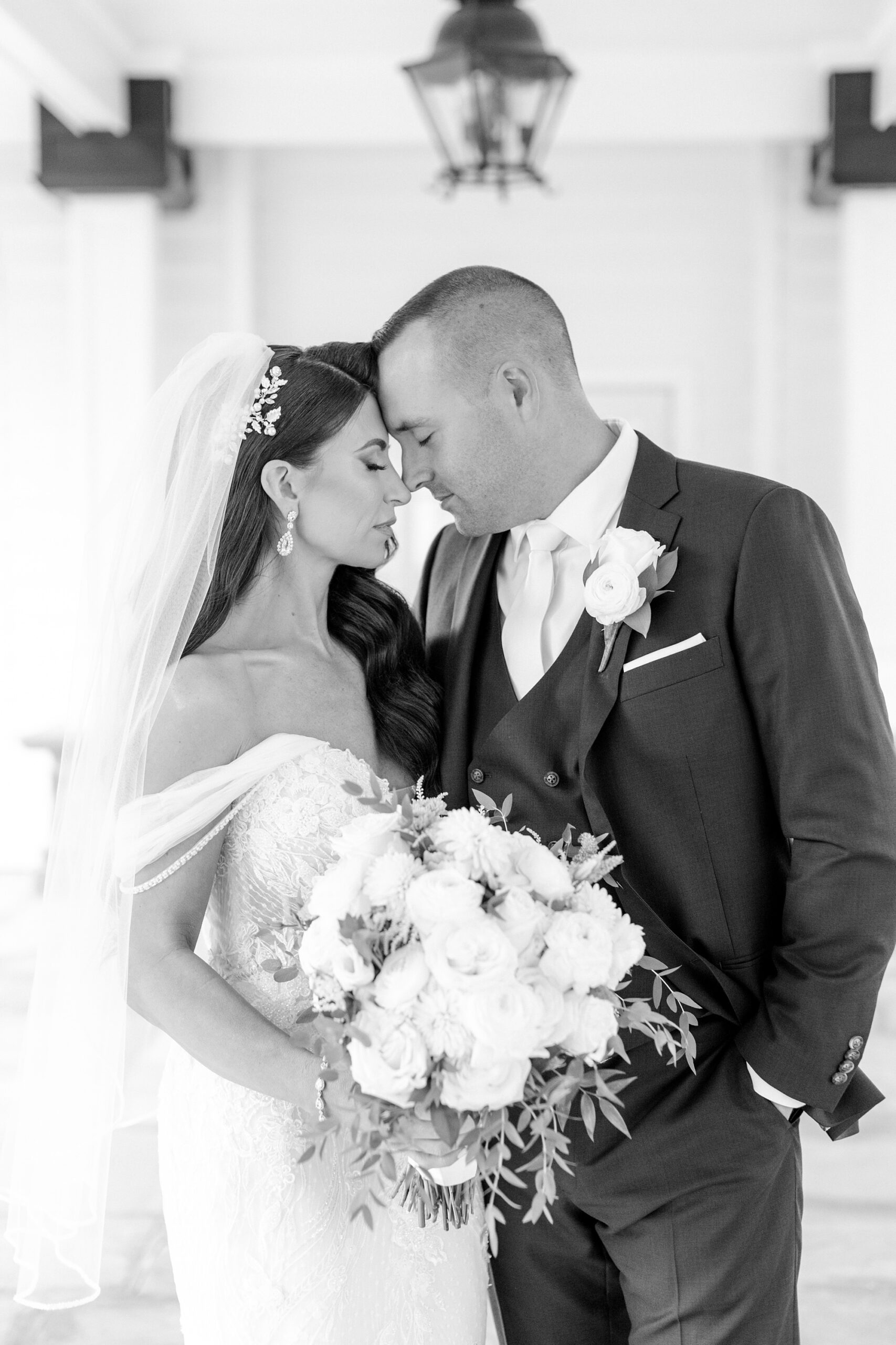 black and white portrait of bride and groom hugging leaning heads together