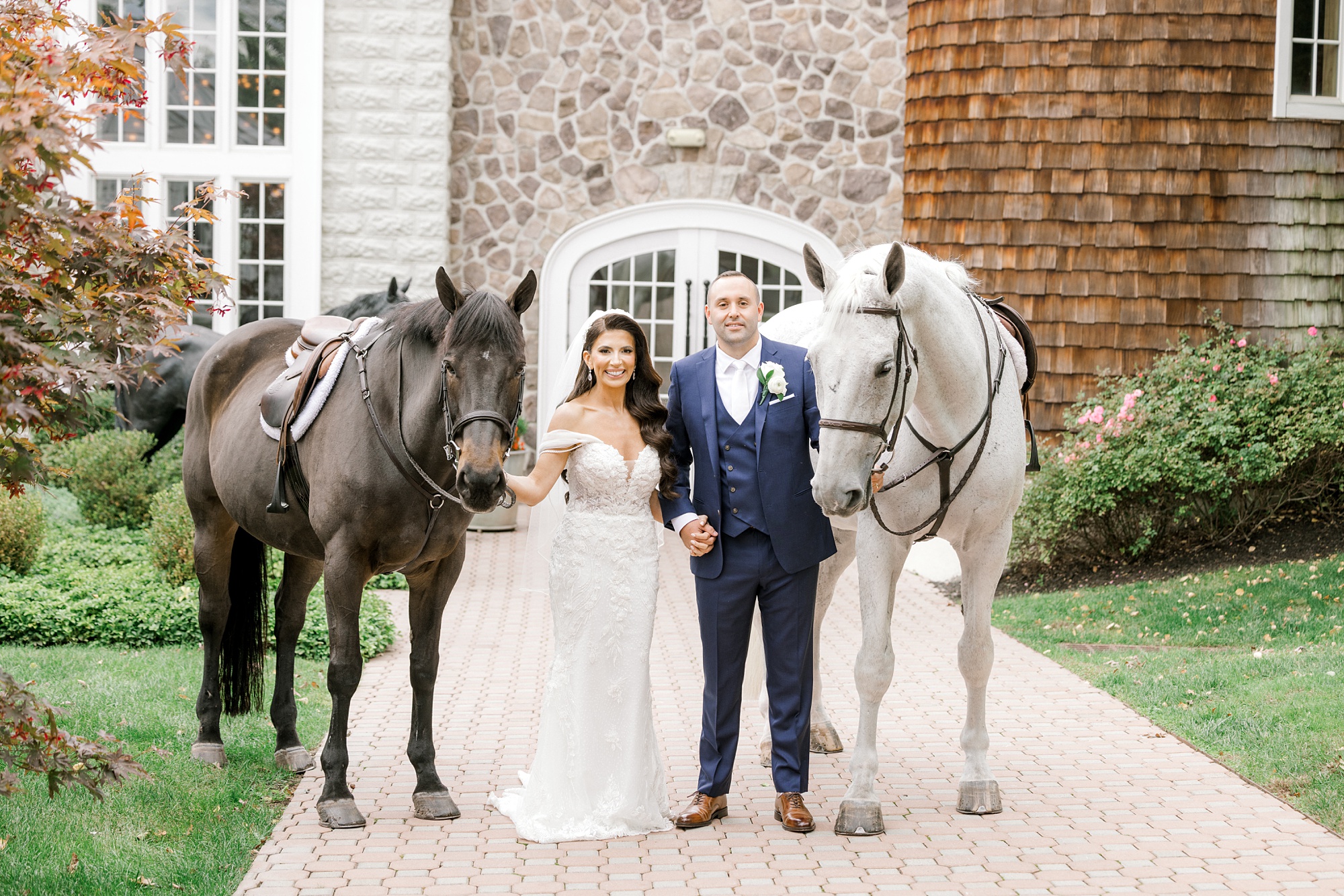 bride and groom hold reins of two horses outside Ryland Inn