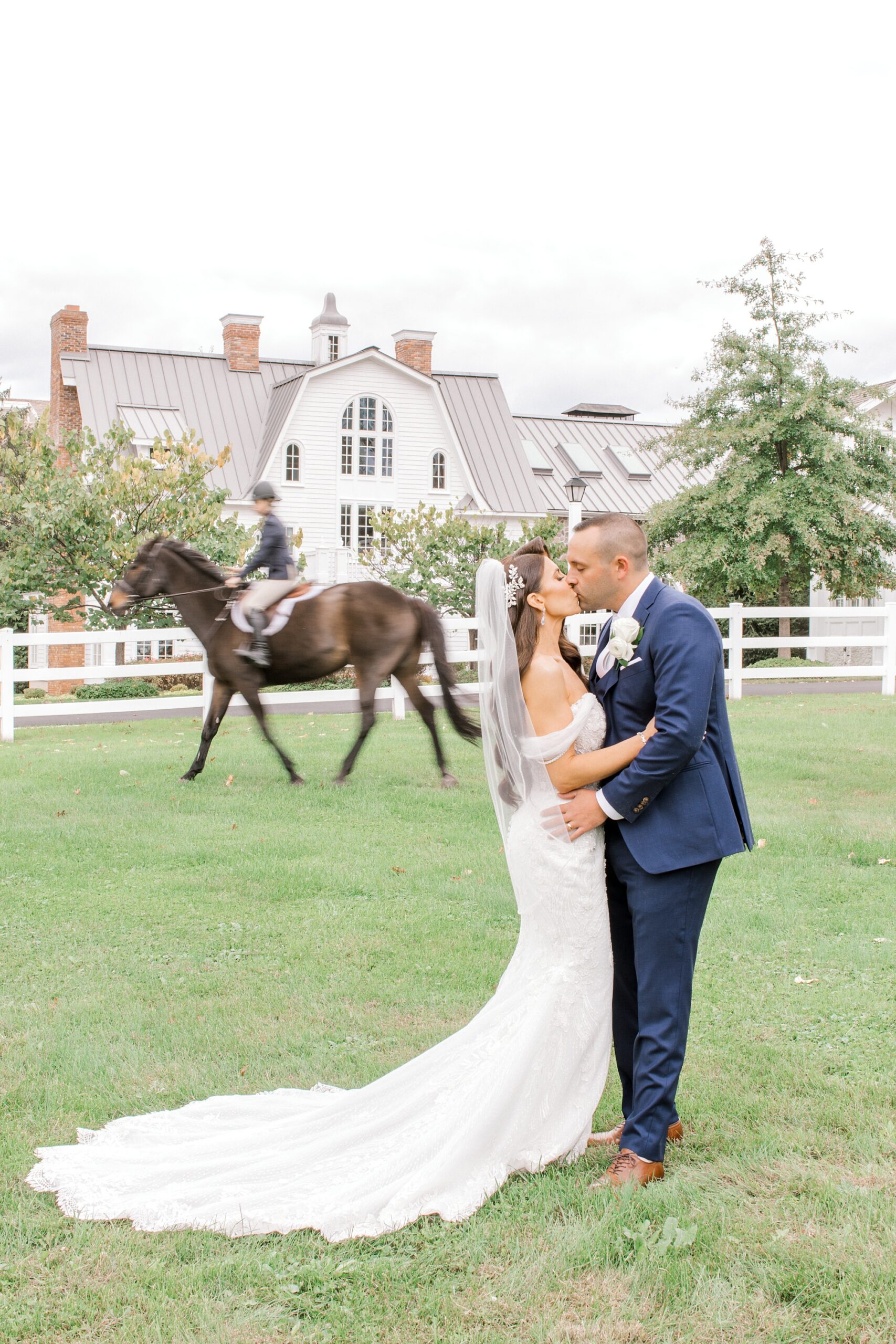 newlyweds kiss while brown horse runs behind them at Ryland Inn