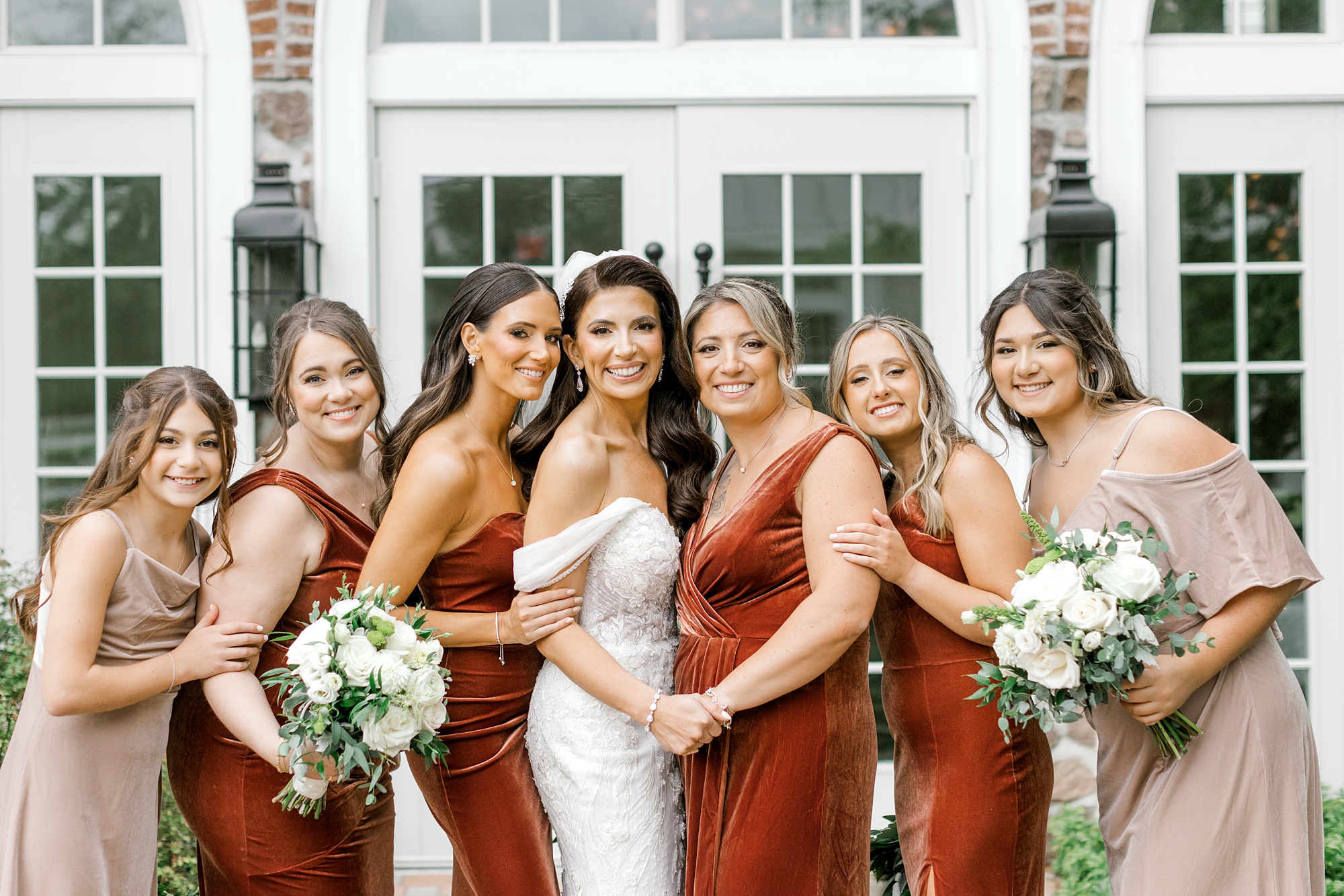 bride and bridesmaids hold bouquets of white roses for fall wedding at Ryland Inn