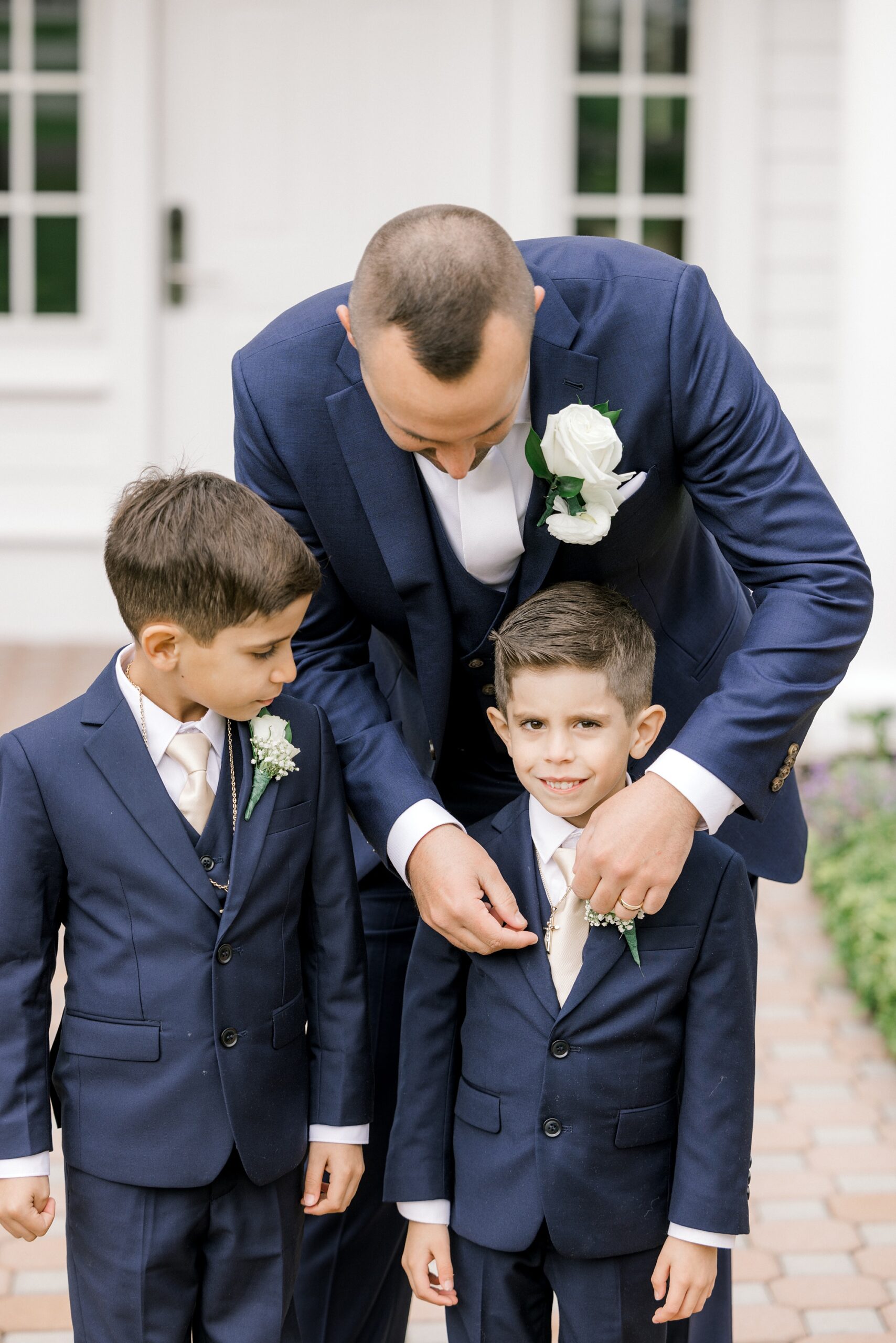 groom helps ring bearers with suits before fall wedding