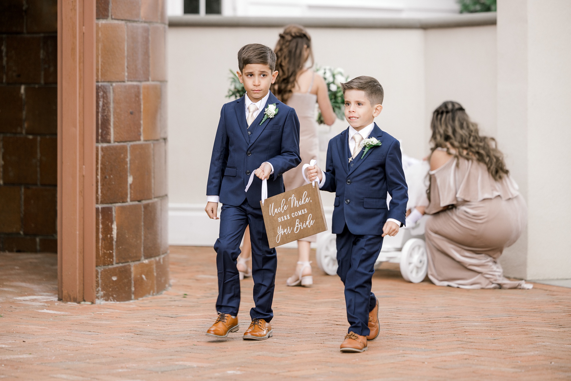 ring bearers carry wooden sign during wedding ceremony at Ryland Inn on the patio
