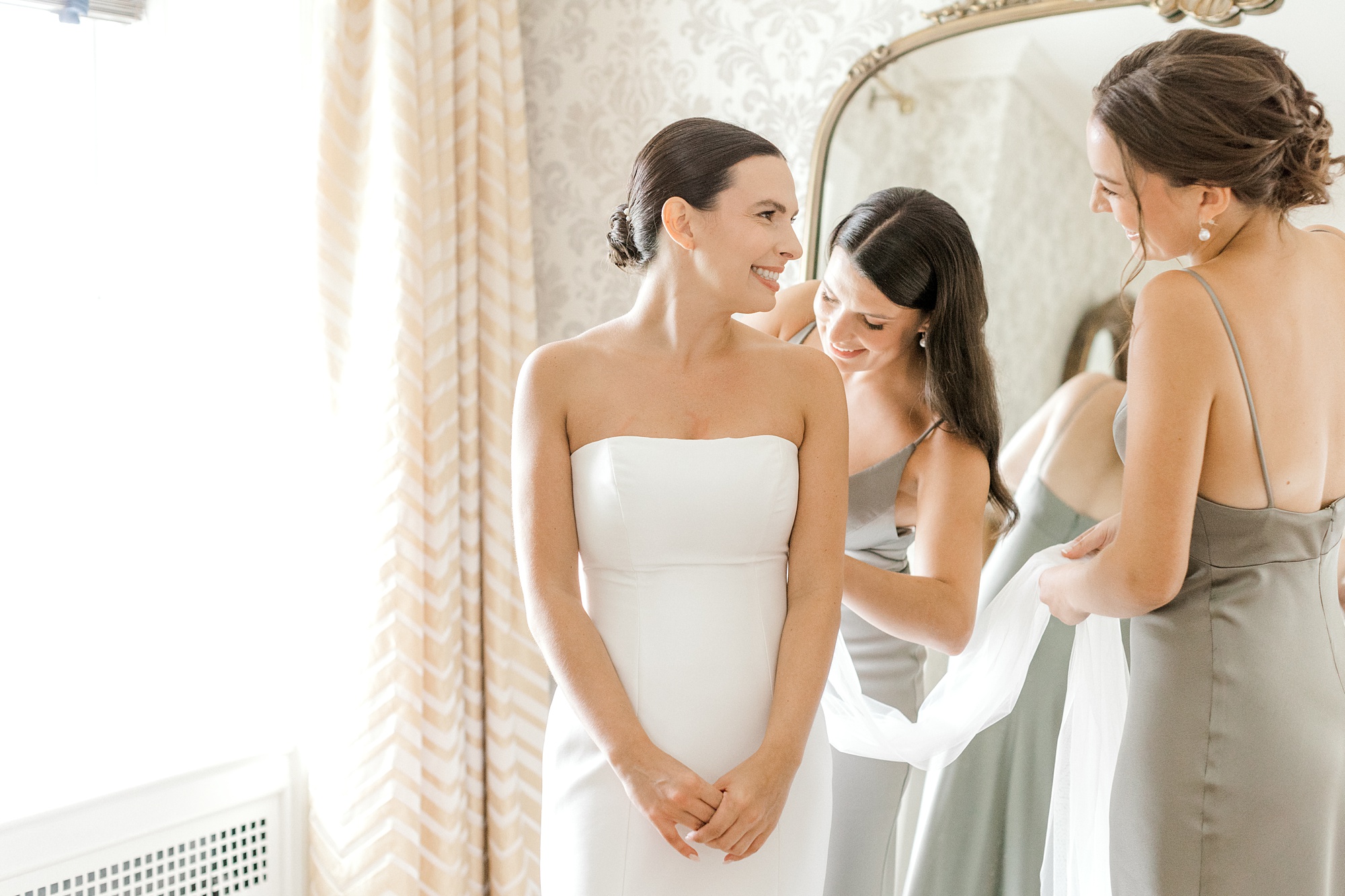bride looks over shoulder at sisters during prep at Fiddler's Elbow Country Club