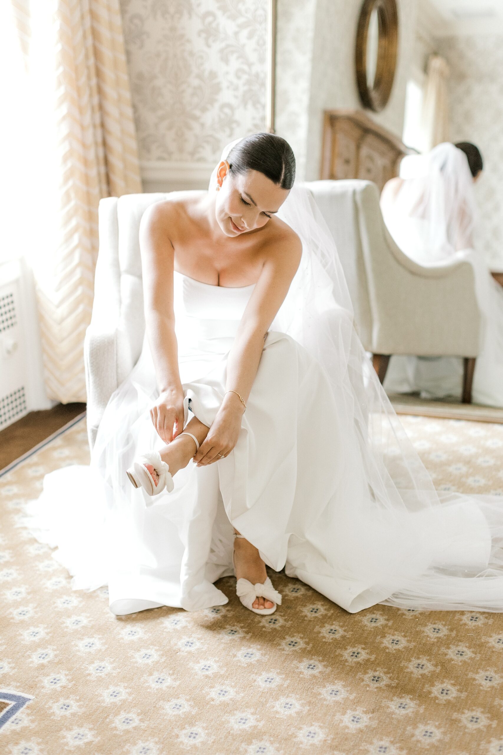 bride puts on shoes sitting in bridal suite at Fiddler's Elbow Country Club