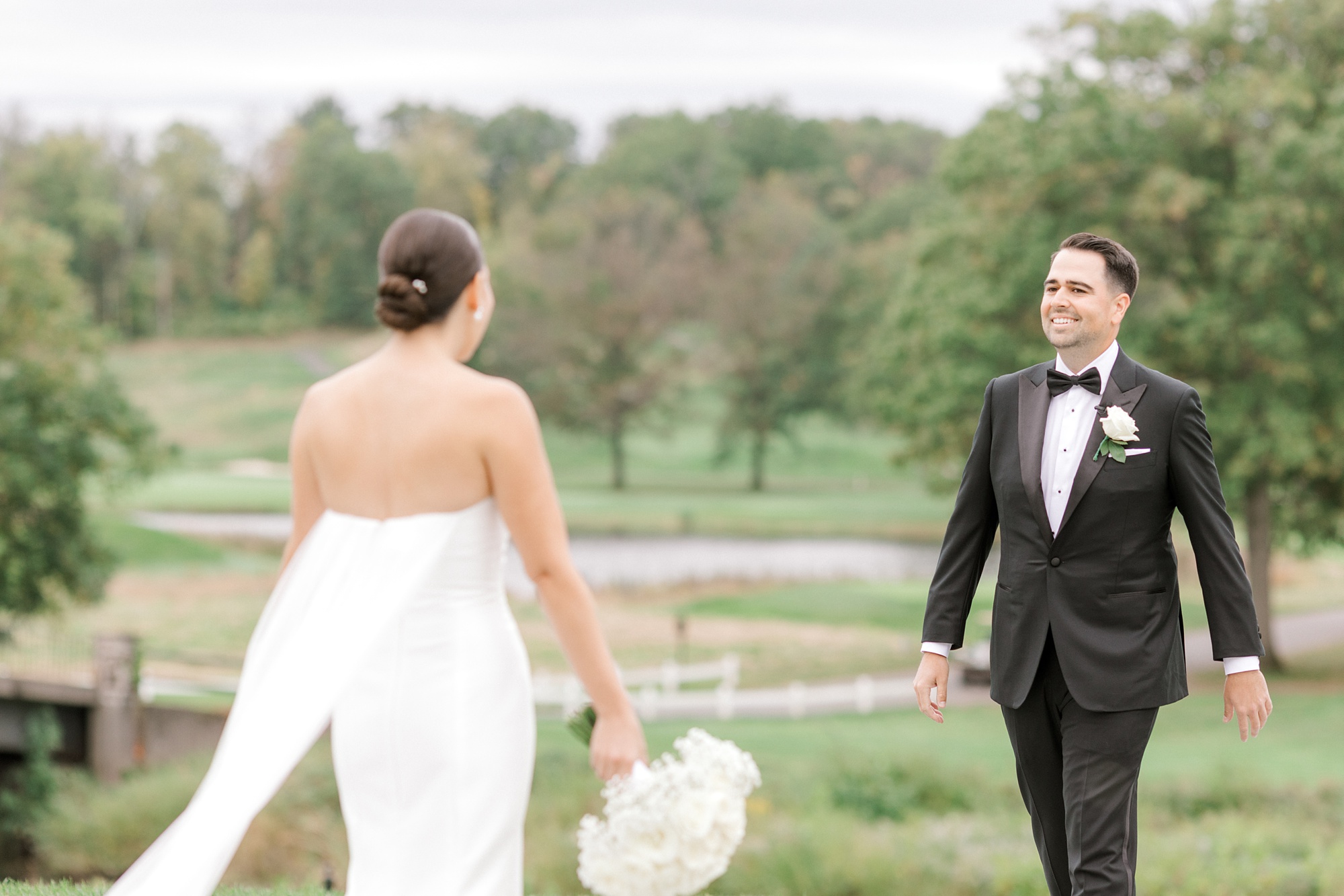 groom turns to see bride during first look near green at Fiddler’s Elbow Country Club 
