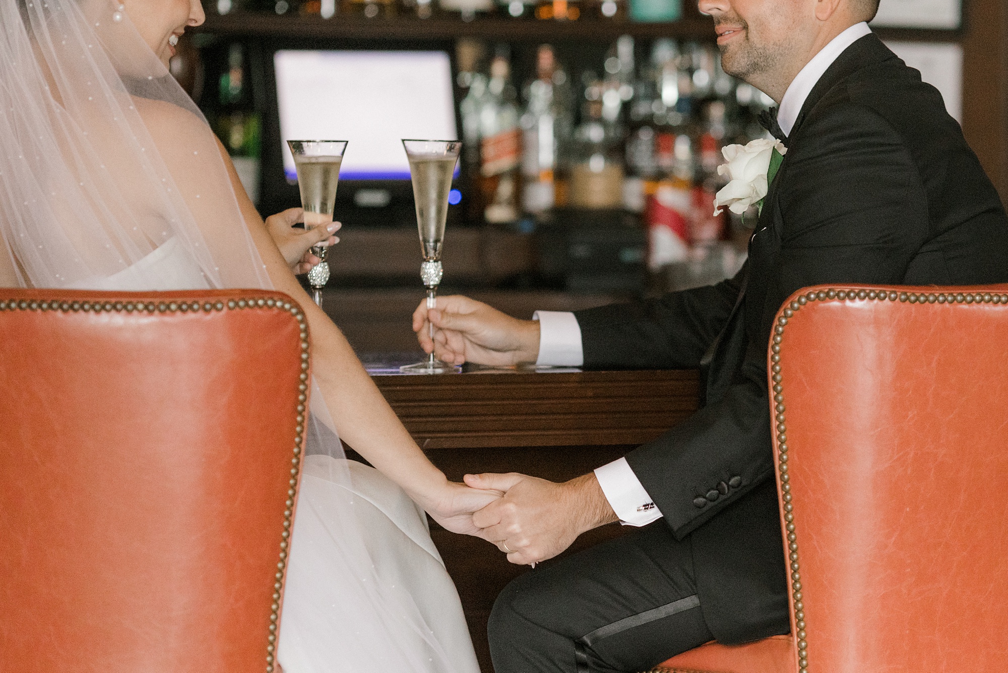 bride and groom hold hands sitting at the bar inside Fiddler’s Elbow Country Club 
